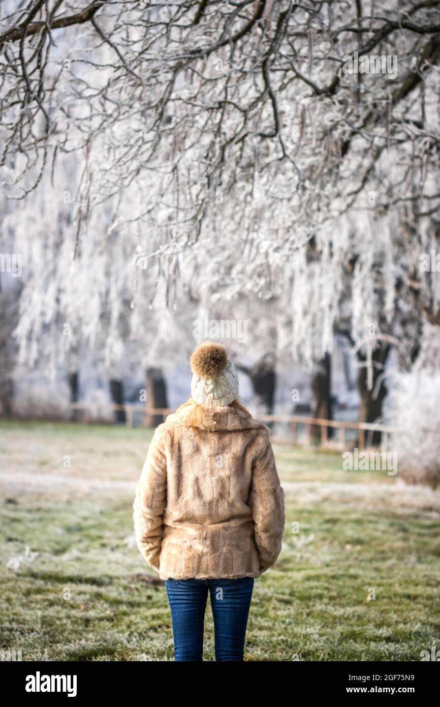 Frau in Kunstpelzmantel und genießen Spaziergang im Winter Park. Schöne verschneite Landschaft mit gefrorenen Bäumen Stockfoto