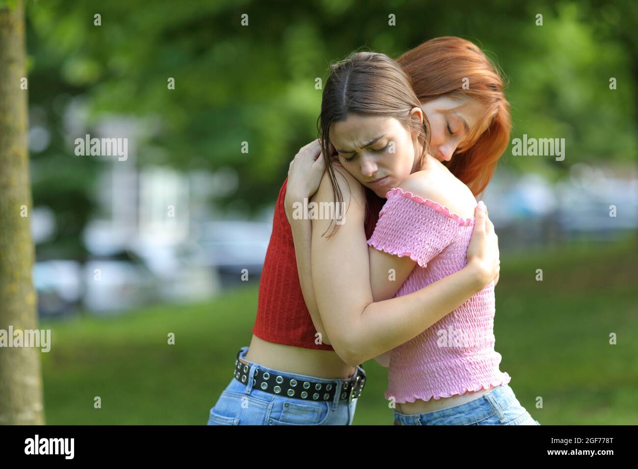 Traurige Frauen, die sich in einem grünen Park umarmen Stockfoto