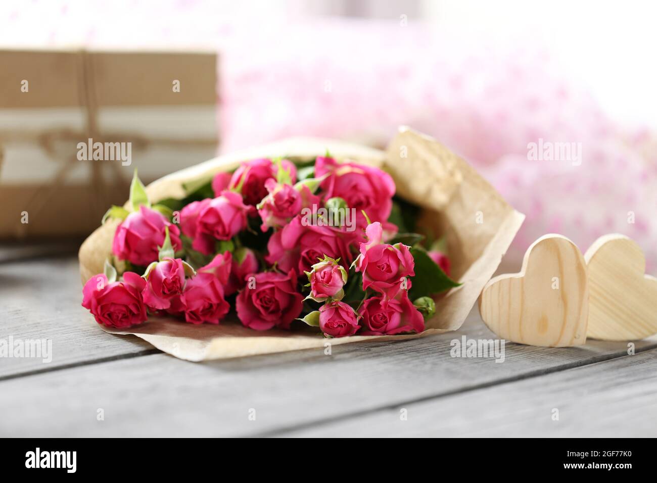 Rosa Rosen in einer Papiertüte und dekorative Herzen auf einen hölzernen  Tisch, in der Nähe Stockfotografie - Alamy