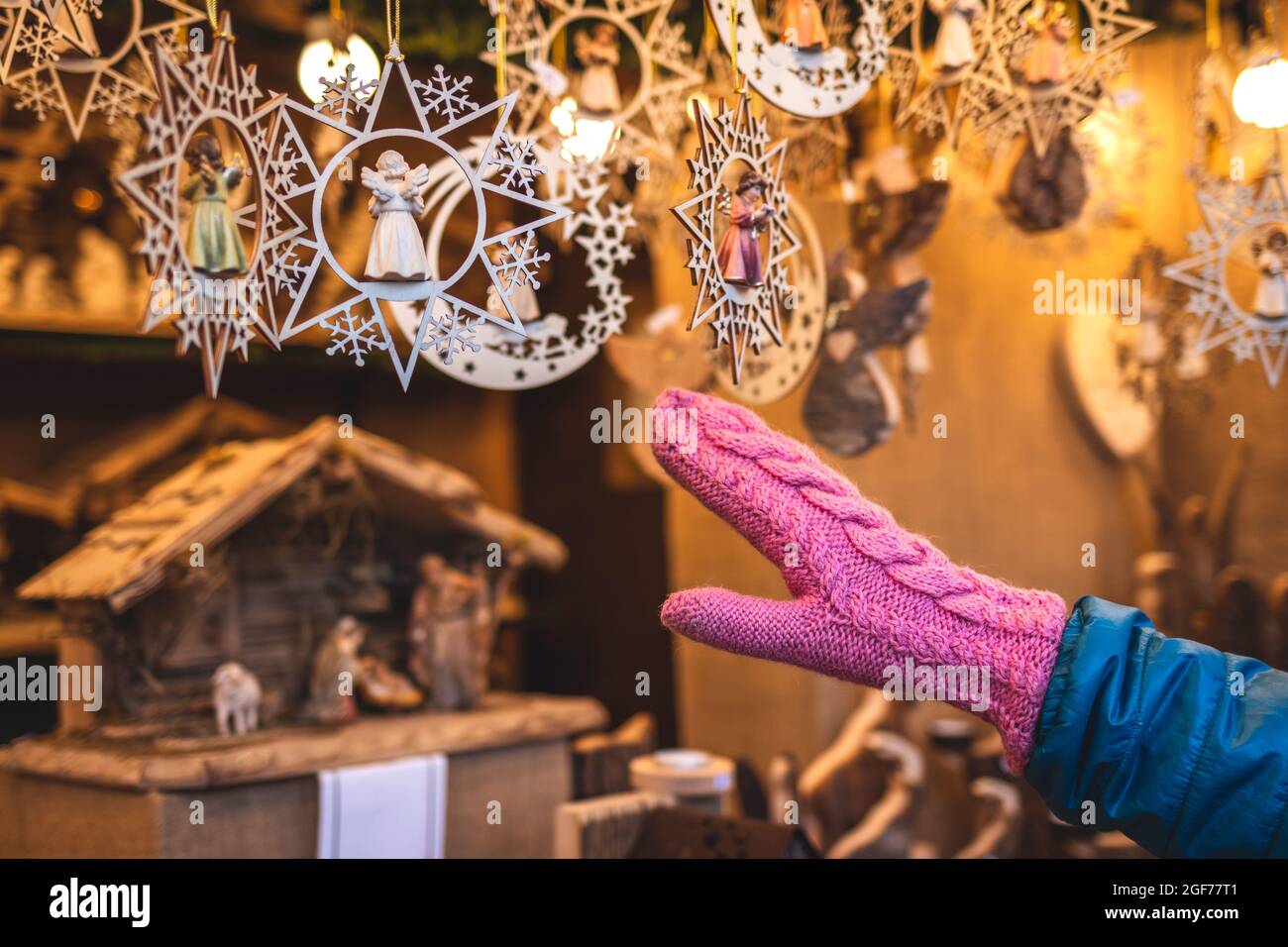 Hand in gestrickten Fäustlingen Handschuh mit Weihnachtsdekoration im Kiosk auf dem Weihnachtsmarkt in Wien, Österreich. Verkauf von Ornamenten während der Adventszeit Stockfoto