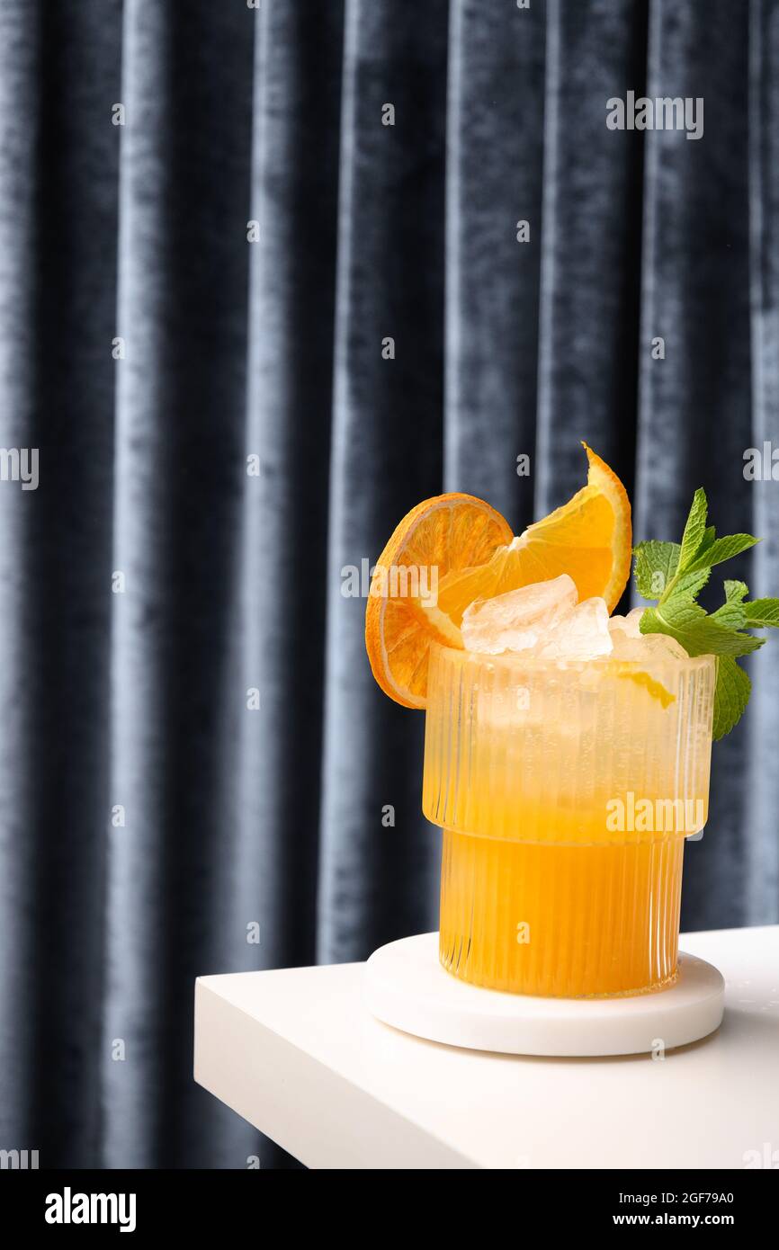 Klassischer Frischecocktail, Mojito, Limonade oder Mai Tai mit Limette, Orange auf Podium auf blauem Hintergrund des Vorhangs. Sommerurlaub Mocktail. Stockfoto
