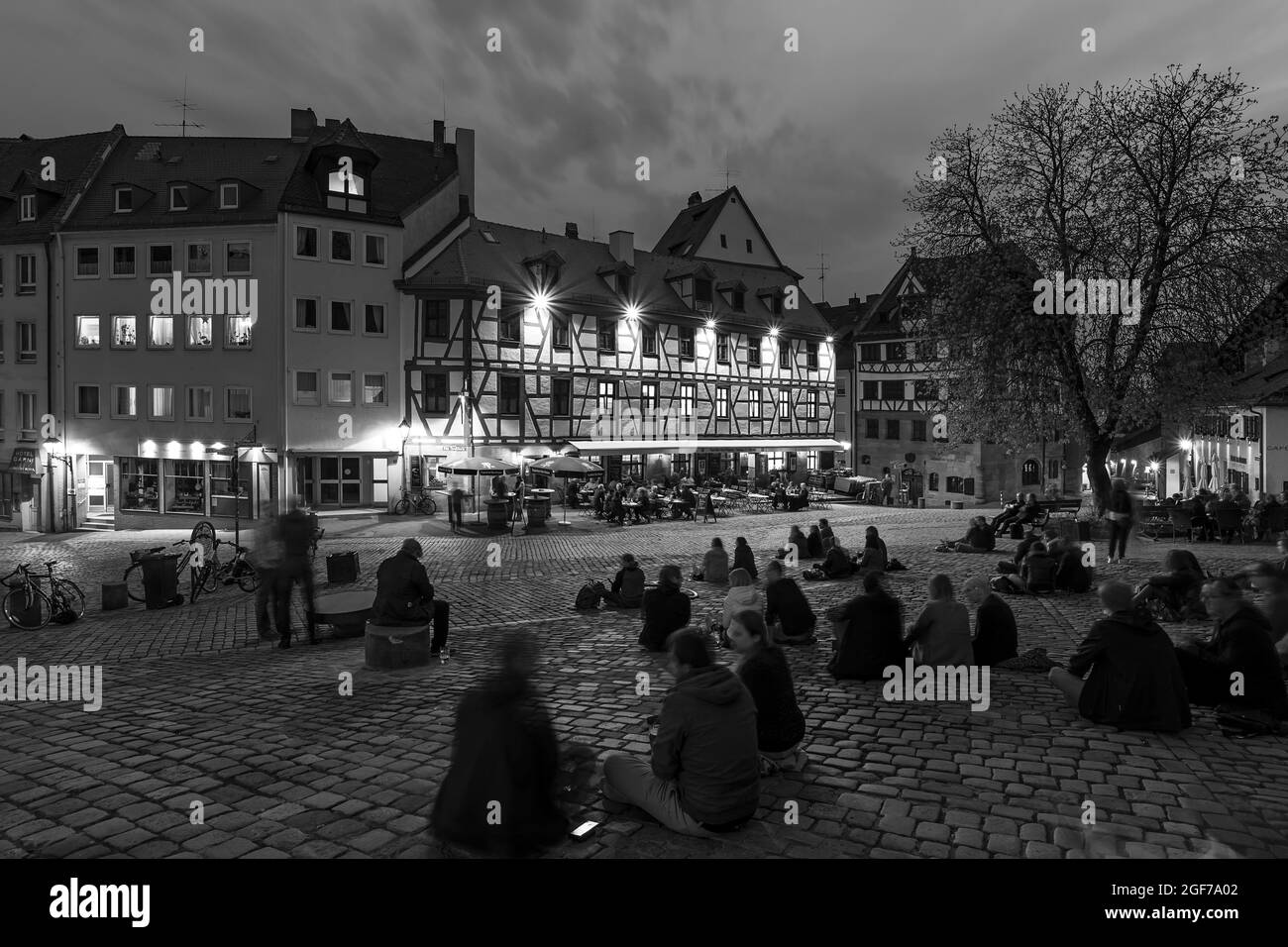 Jugendliche sitzen abends auf einem Platz vor einem historischen Gasthaus, Tiergaertnertorplatz, Nürnberg, Mittelfranken, Bayern, Deutschland Stockfoto