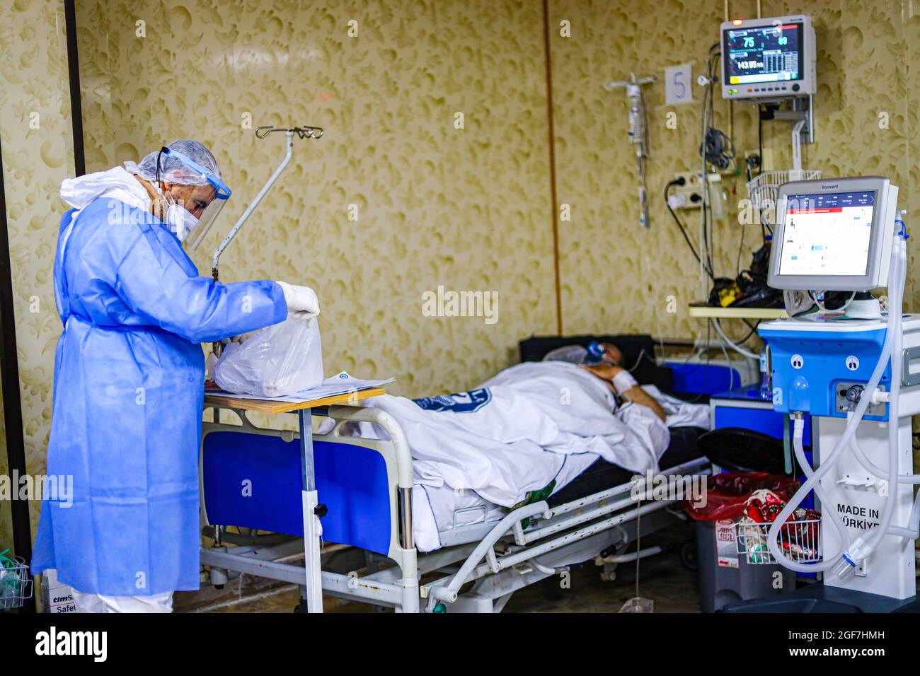 Idlib, Syrien. August 2021. In einem Isolationskrankenhaus in der Stadt Idlib kümmert sich ein Arzt in einem Schutzanzug um einen älteren Mann.die Delta-Mutante kam in Idlib an, wo im Idlib-Labor für 92 Proben eine Genotypisierung durchgeführt wurde. Die Alpha-Mutante wurde in 6 Proben und die Delta-Mutante in 47 Proben gefunden, und es gibt einen signifikanten Anstieg der Anzahl der bestätigten Fälle von Covid-19 in den letzten Tagen. (Bild: © Omar Albam/SOPA Images via ZUMA Press Wire) Stockfoto