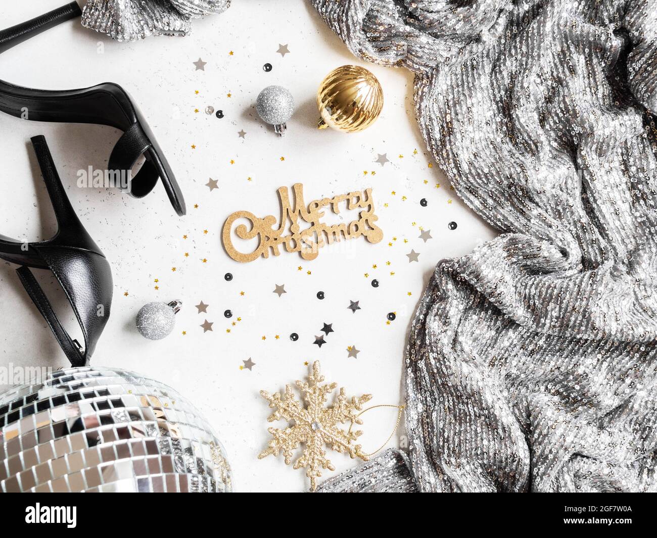 Flaches Lay von Weihnachten Party Disco Ball, schwarze Schuhe, Kleid, Saison Dekoration und wünschen Ihnen frohe Weihnachten auf weißem Hintergrund. Draufsicht. Stockfoto