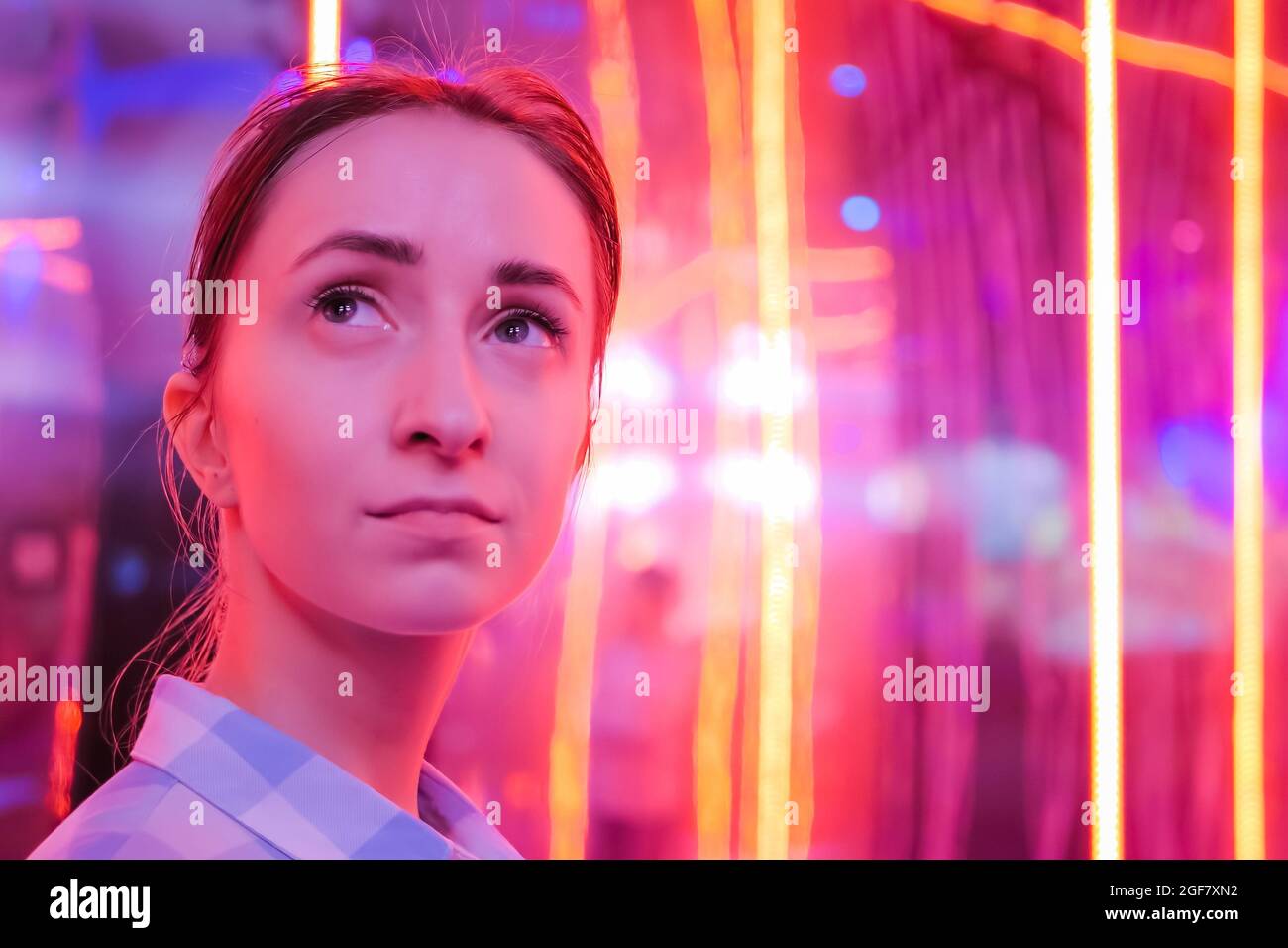 Portrait einer Frau, die sich in der Ausstellung oder im Museum umsieht Buntes Licht Stockfoto