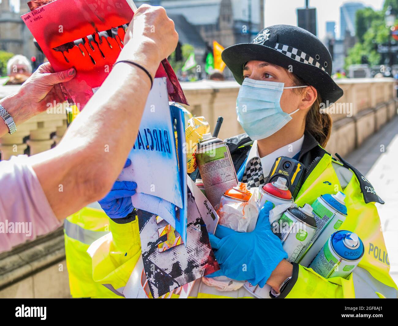 London, Großbritannien. August 2021. Anti-Barclays und Anti-Öl-Worte werden auf den Bürgersteig vor den Büros des HMRC gesprüht die Polizei sammelt die Spraydosen und warnen einige der Demonstranten - XR Cymru protestiert vor HM Revenue and Customs in Whitehall über die Regierungen, die mit der fossilen Energiewirtschaft zu tun haben, und auch Barclays Aufzeichnungen darüber Finanzierung - Extinction Rebellion startet zwei Wochen lang unter dem Namen Impossible Rebellion in London. Kredit: Guy Bell/Alamy Live Nachrichten Stockfoto