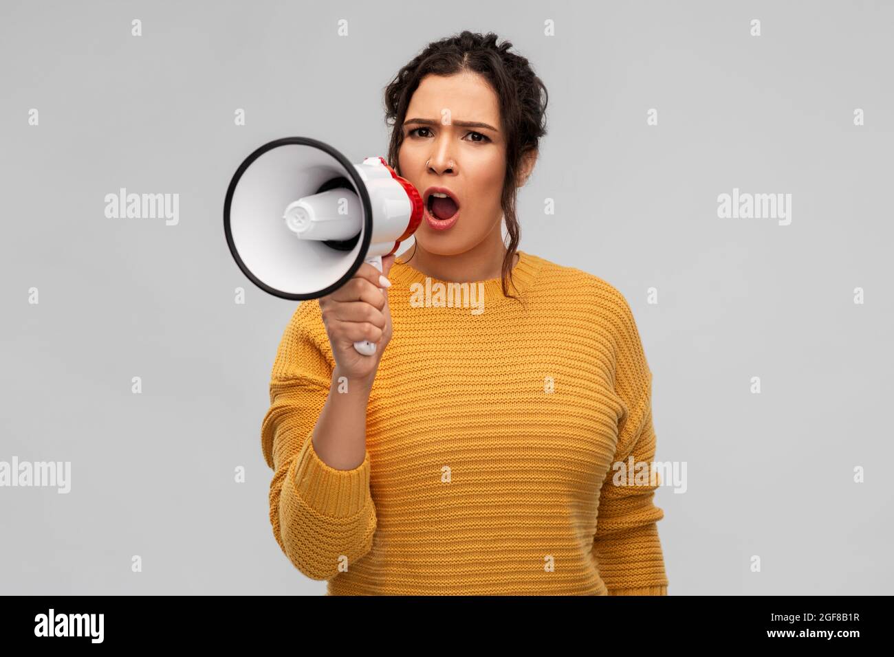 Wütende junge Frau, die mit dem Megaphon spricht Stockfoto