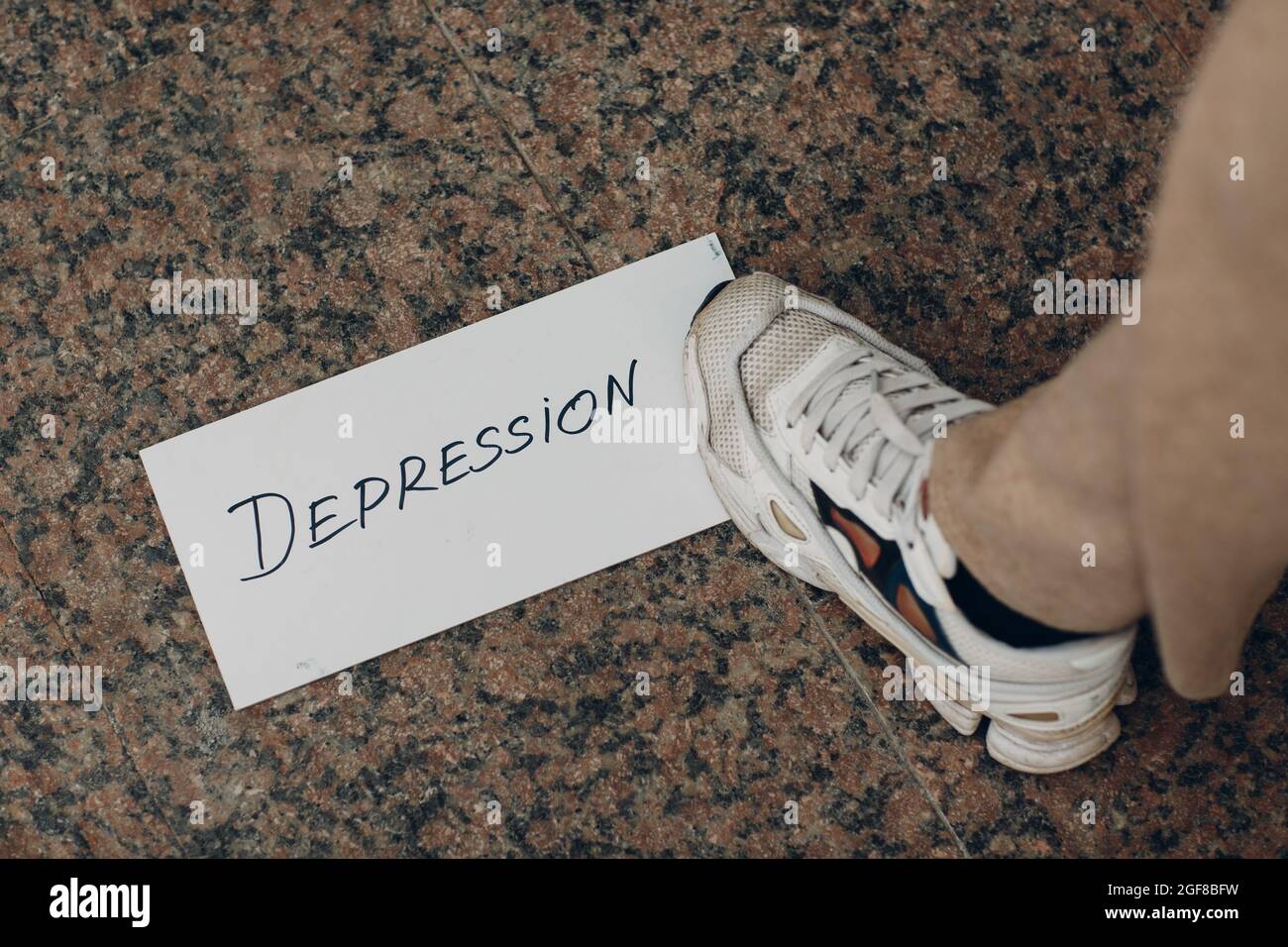 Frau tritt auf weißes Blatt Papier mit dem Wort Depression und Fuß darauf. Stockfoto