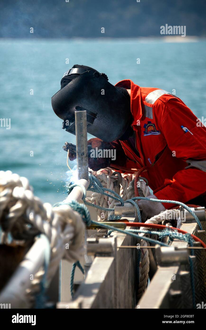Personen, die Rohrleitungen auf See schweißen, tragen vollständige PSA oder persönliche Schutzausrüstung Stockfoto