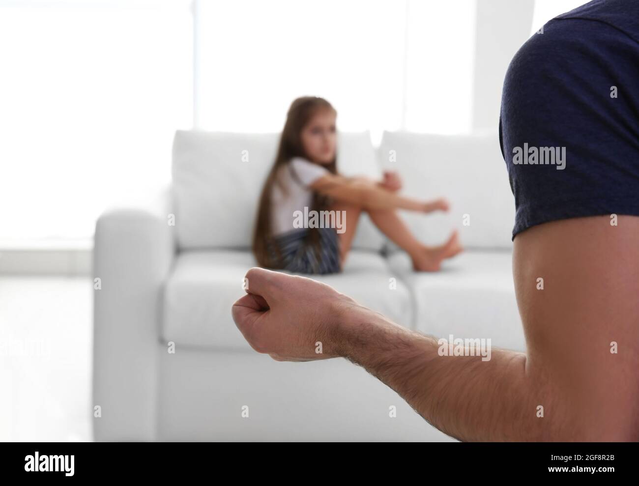 Die Faust des Vaters als Strafe und seine junge Tochter auf der Couch