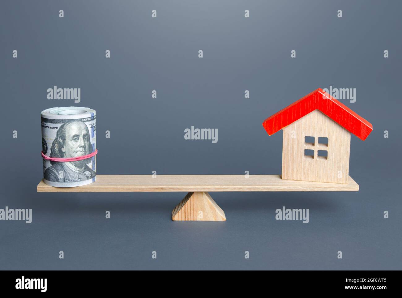 Haus- und Geldbilanz auf der Waage. Kauf und Verkauf, fairer Preis. Gebäudewartung. Bewertung von Immobilien. Abschätzung der Aufwendungen fo Stockfoto