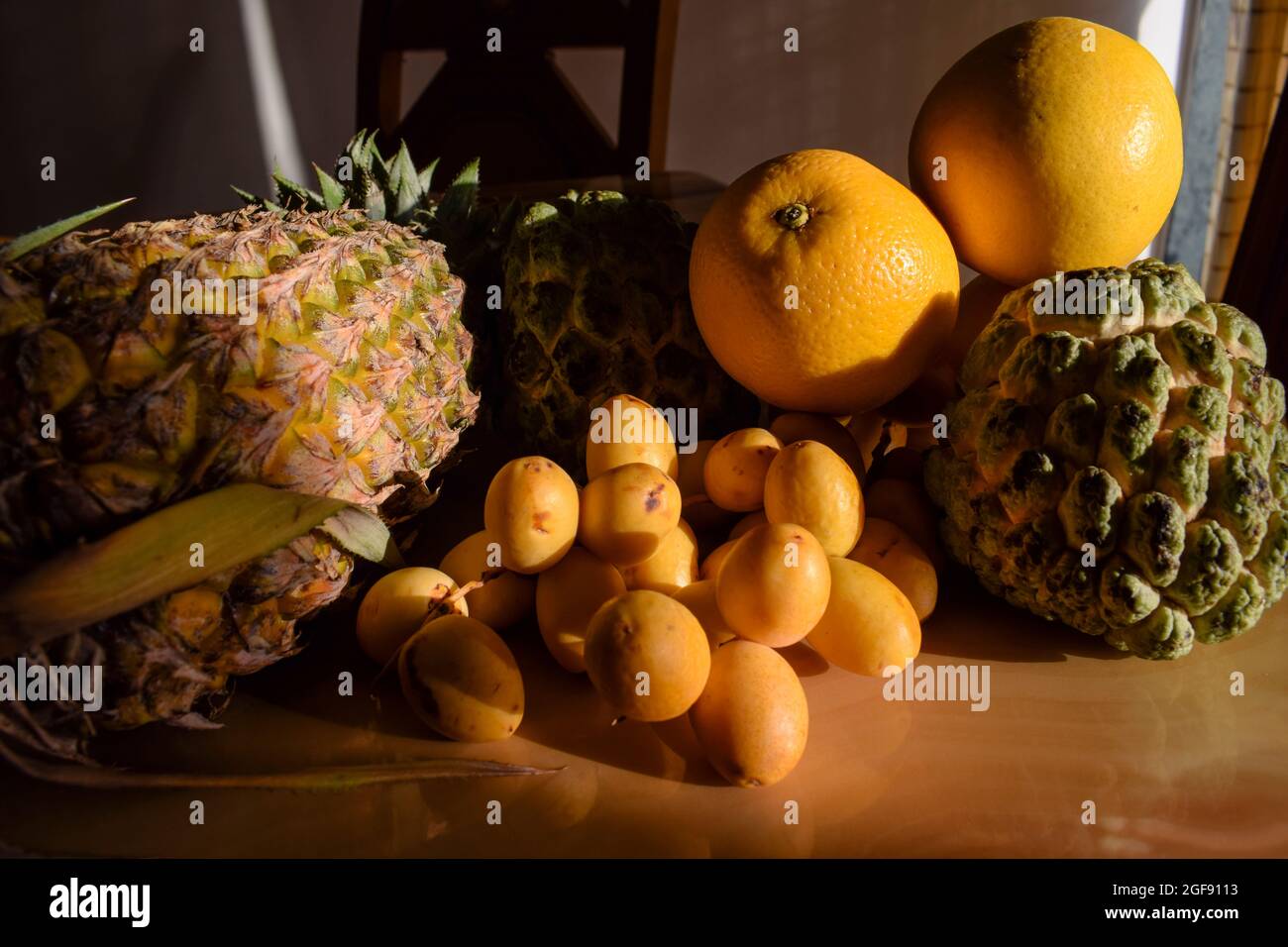 Verschiedene Früchte wie Ananas, malta, Orangen, Puddingäpfel, frische gelbe knusprige Datteln auf dem Esstisch für das Frühstück am Morgen. Esstisch im Innenbereich Stockfoto