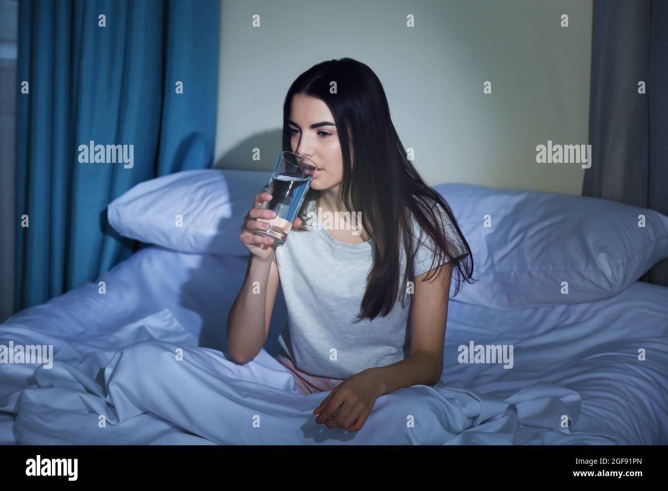 Junge Frau, die nachts ein Glas Wasser im Bett trinkt Stockfotografie -  Alamy