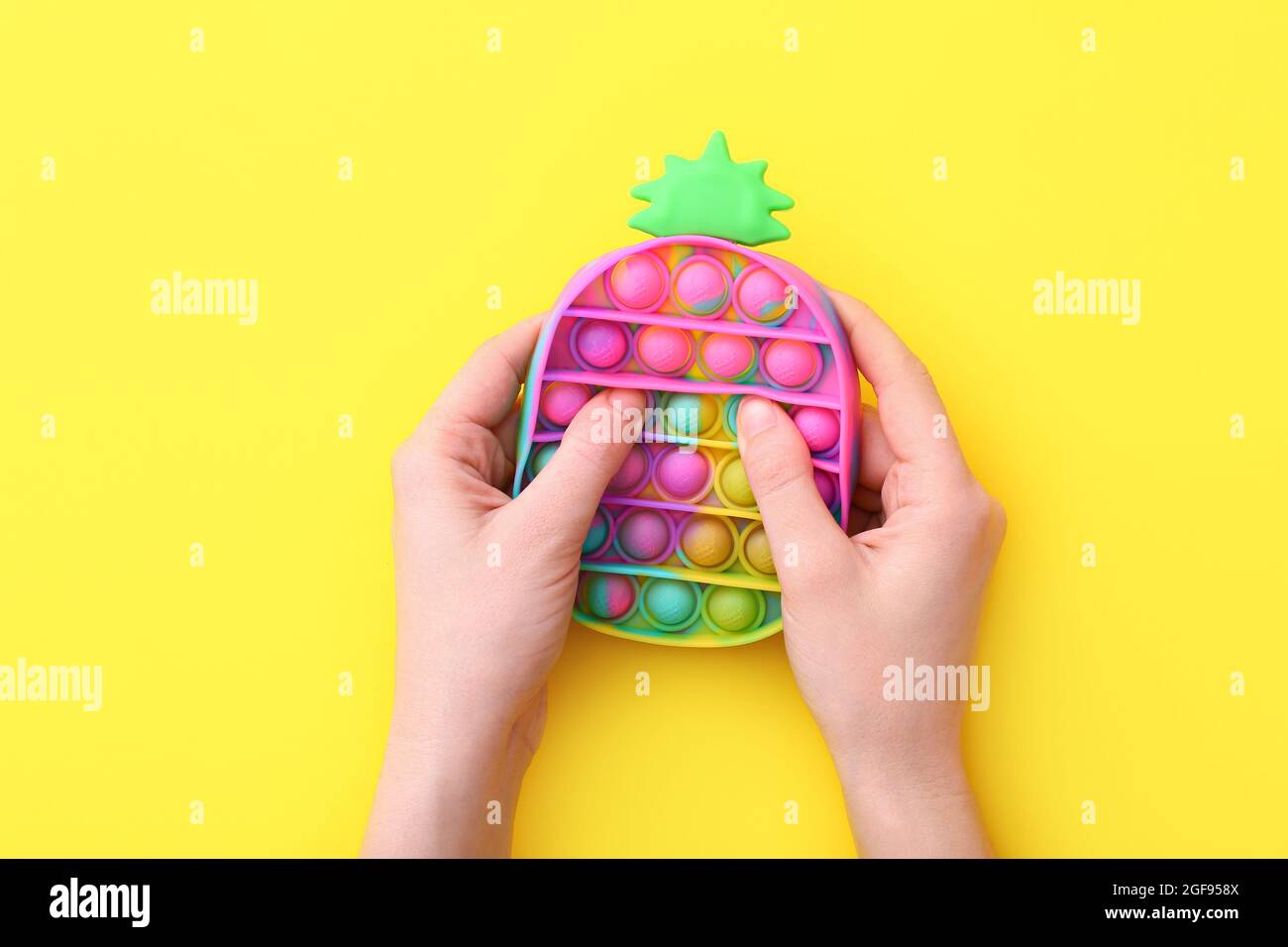 Neue trendige beliebte Silikon bunte Anti Stress Pop IT Spielzeug für Kind auf gelbem Hintergrund. Blick von oben. Stockfoto