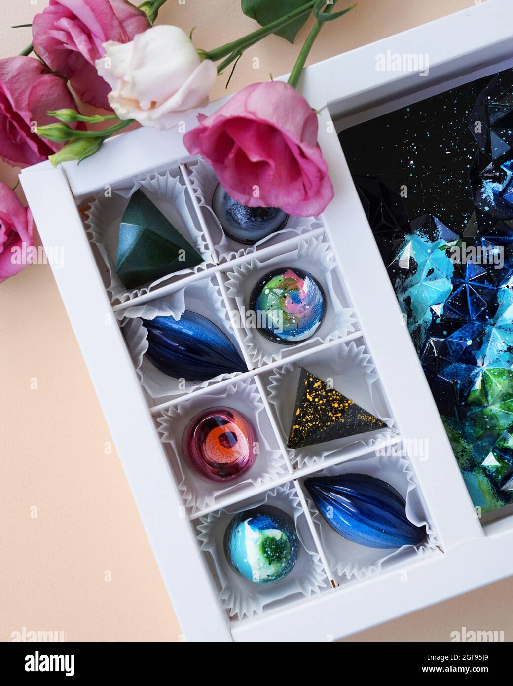 Geschenkschachtel mit handgefertigten Pralinen. Geometrisches und Raumdesign. Box auf einem hellen Hintergrund. Süßigkeiten und Süßigkeiten aus nächster Nähe. Vertikales Foto Stockfoto