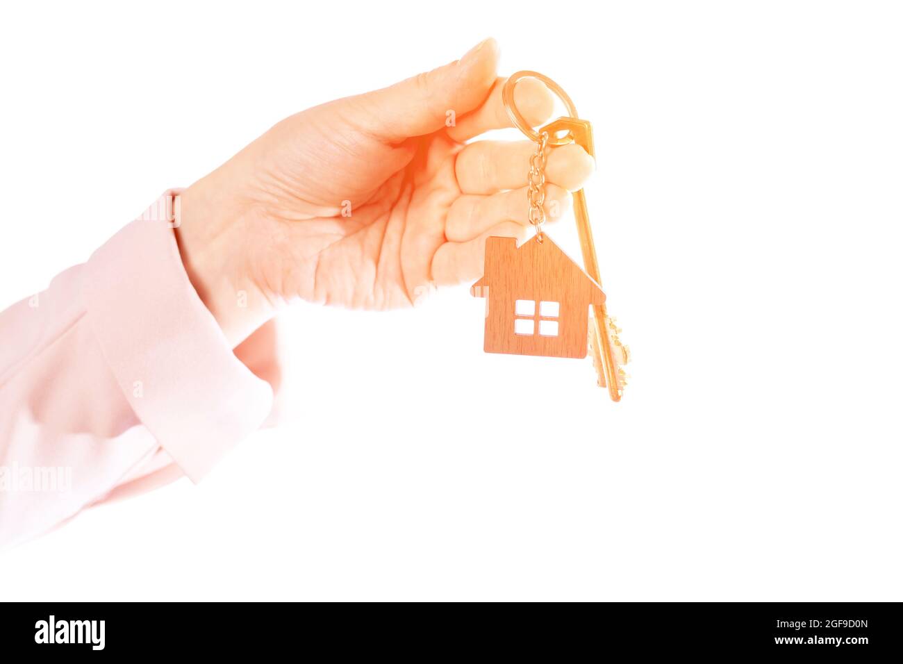 Die Hand der Frau hält den Schlüssel zur Wohnung, isoliert auf weißem Hintergrund Stockfoto