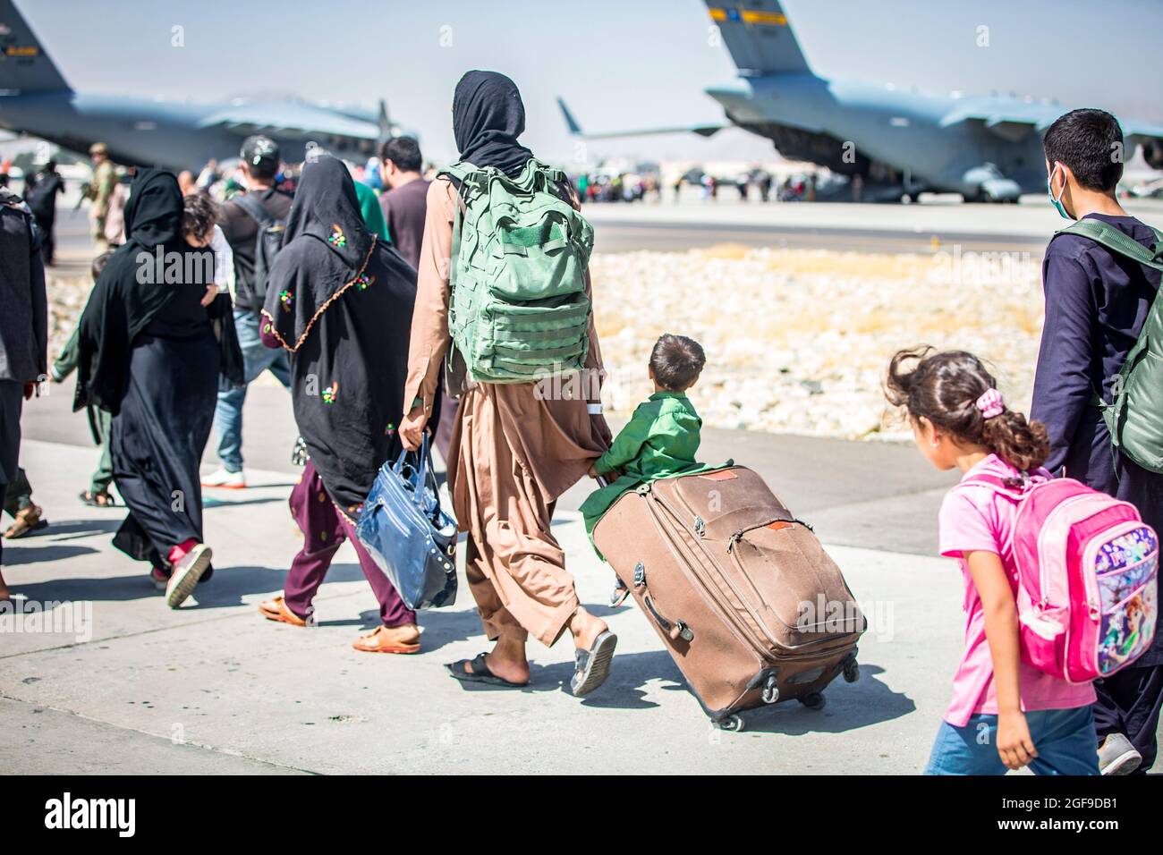 Ein Kind schaut auf das Flugzeug, während es während einer Evakuierung am Hamid Karzai International Airport, Kabul, Afghanistan, im August 24, auf seinen Flug zuläuft. US-Dienstmitglieder unterstützen das Außenministerium bei einer geordneten Abseichung von designiertem Personal in Afghanistan. (USA Marine Corps Foto von Sgt. Samuel Ruiz). Stockfoto