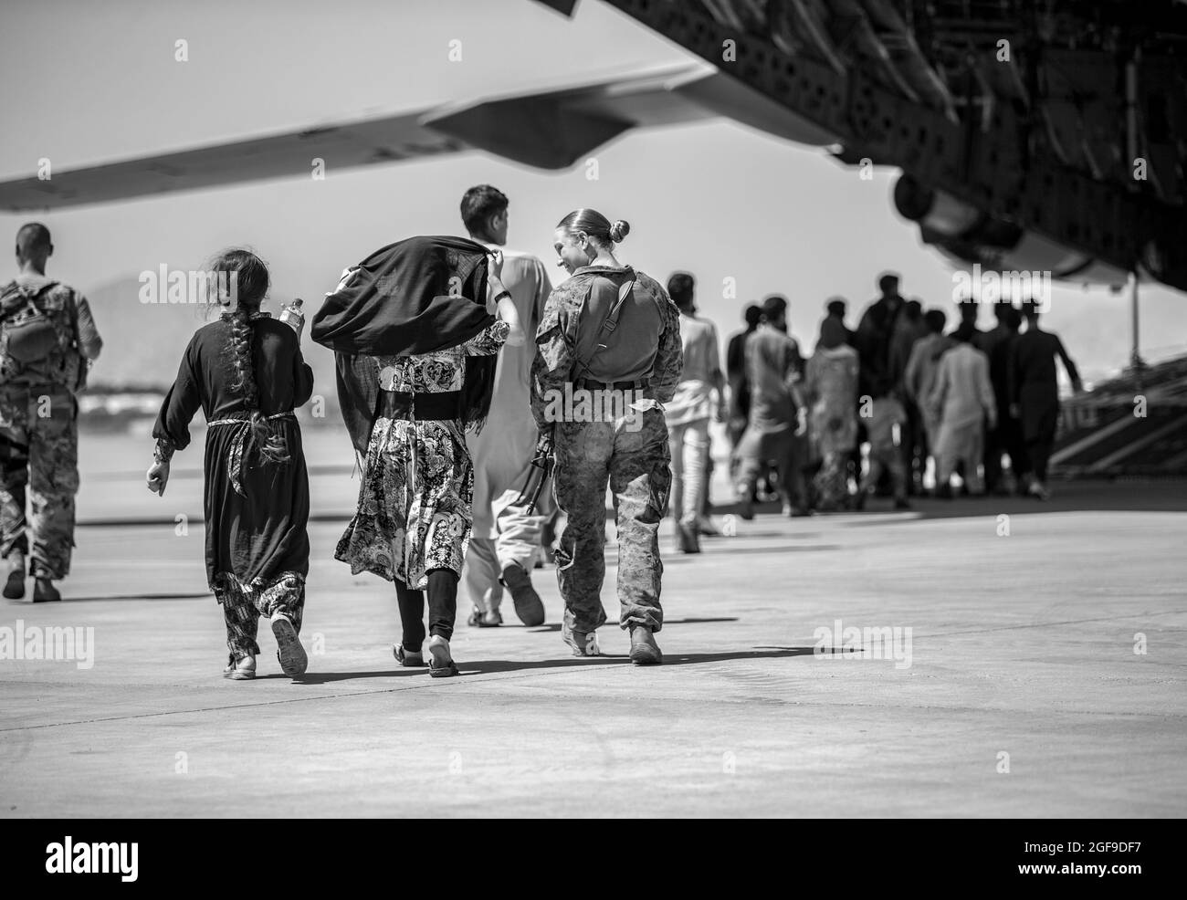 Eine Marine mit der 24. Marine Expeditionary Unit (MEU) geht mit den Kindern während einer Evakuierung am Hamid Karzai International Airport, Kabul, Afghanistan, August 24. US-Dienstmitglieder unterstützen das Außenministerium bei einer geordneten Abseichung von designiertem Personal in Afghanistan. (USA Marine Corps Foto von Sgt. Samuel Ruiz). Stockfoto