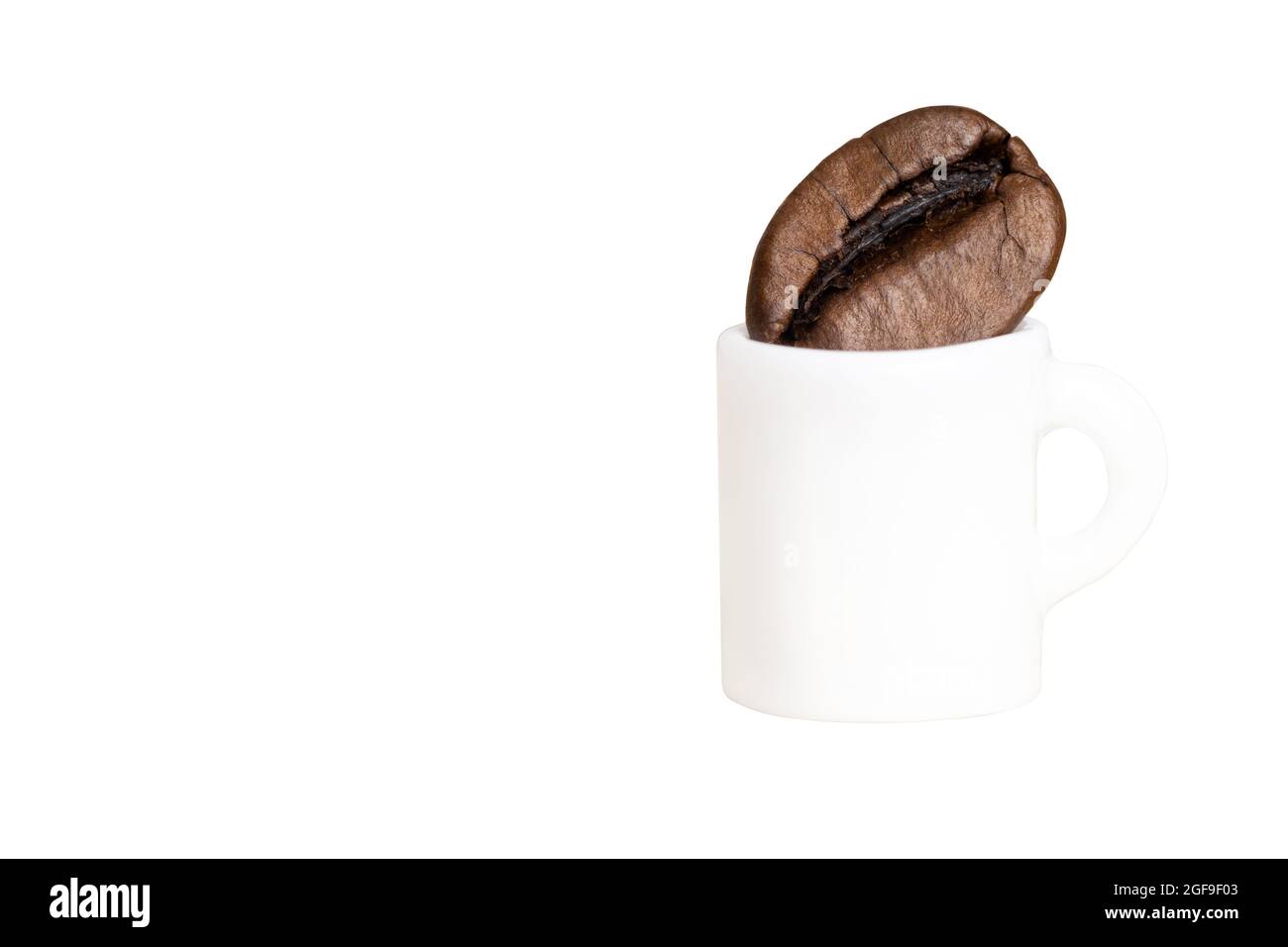 Miniatur-Kaffeetasse mit einer Kaffeebohne, die auf Weiß isoliert ist. Proportionssinn. Stockfoto