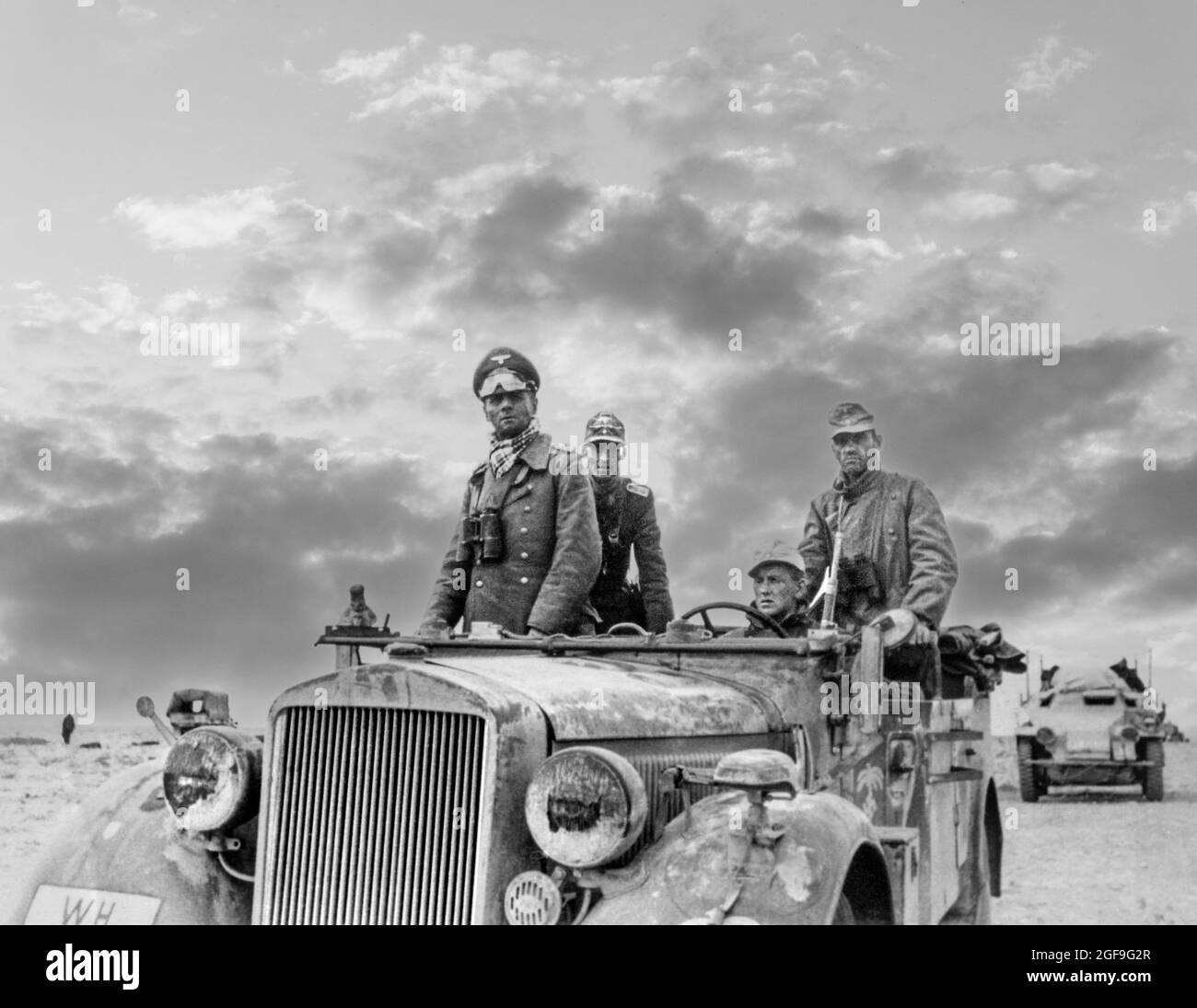 ROMMEL General Rommel ‘ Generalfeldmarschall ‘ Feldmarschall Erwin Rommel in Uniform mit Fernglas und Wüstenvisier, stehend in offenem Wüstenranger Jeep Fahrzeug Nordafrika (der Wüstenfuchs) WW2 mit der Panzer Division 15th zwischen Tobruk und Sidi Omar. Libyen, der zweite Weltkrieg von 1941 mit verstärkter dramatischer Lufteffekte dahinter Stockfoto