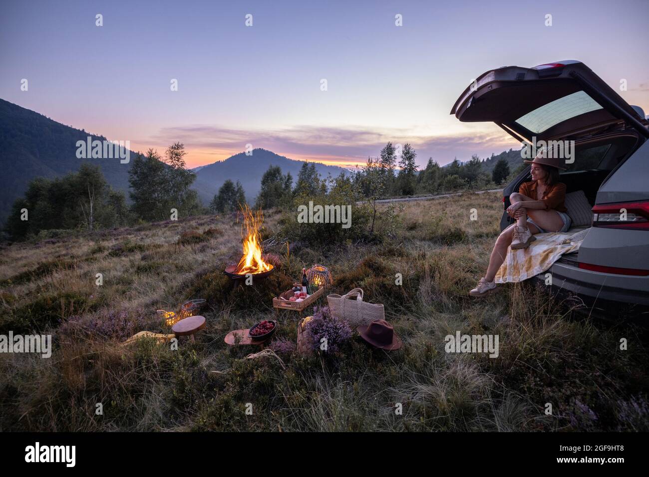 Frau, die mit dem Auto unterwegs ist und ein Picknick in den Bergen hat Stockfoto