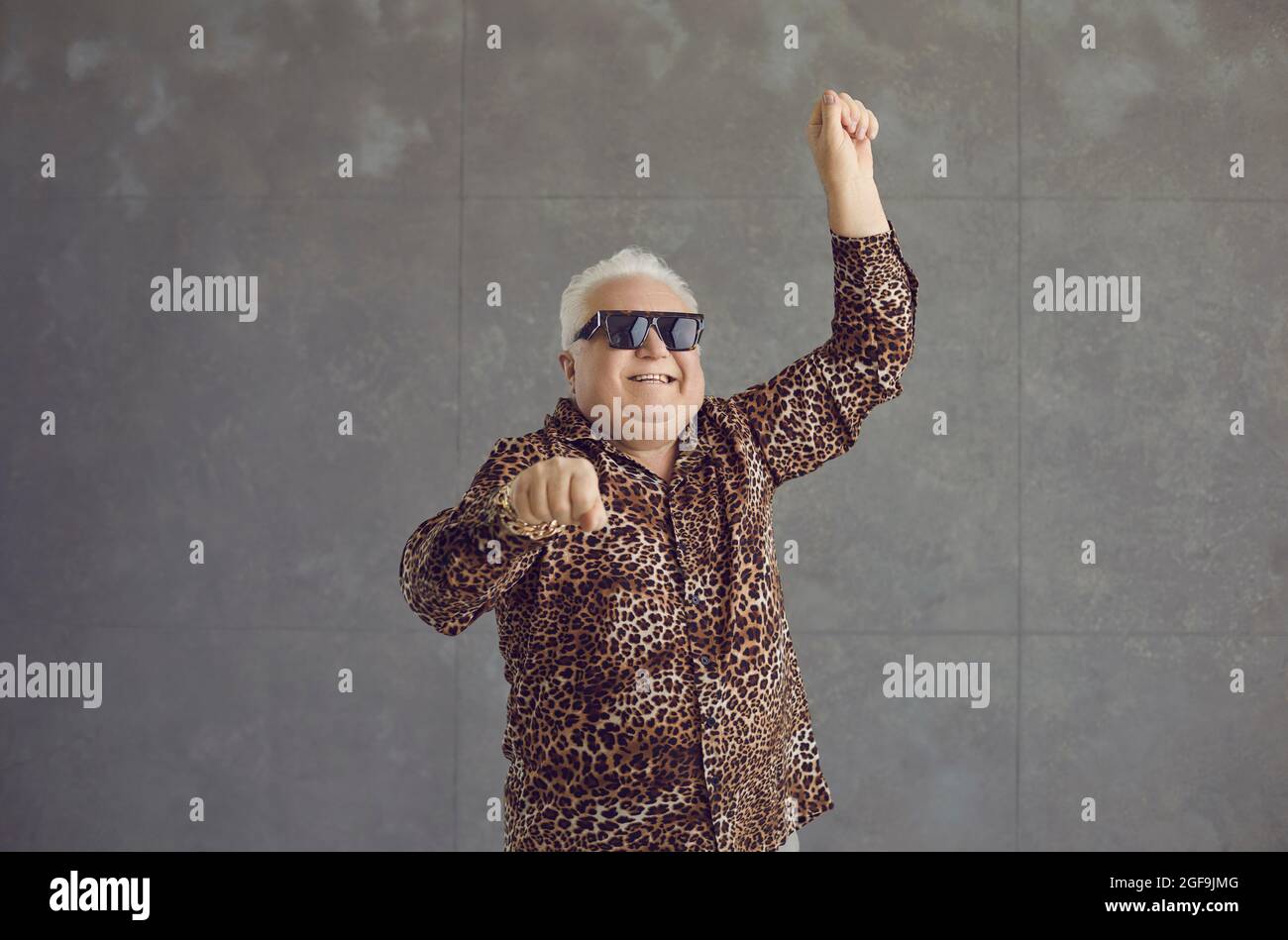 Porträt eines lustigen älteren Mannes im Leopardenhemd und coolen Gläsern, die tanzen und Spaß haben Stockfoto