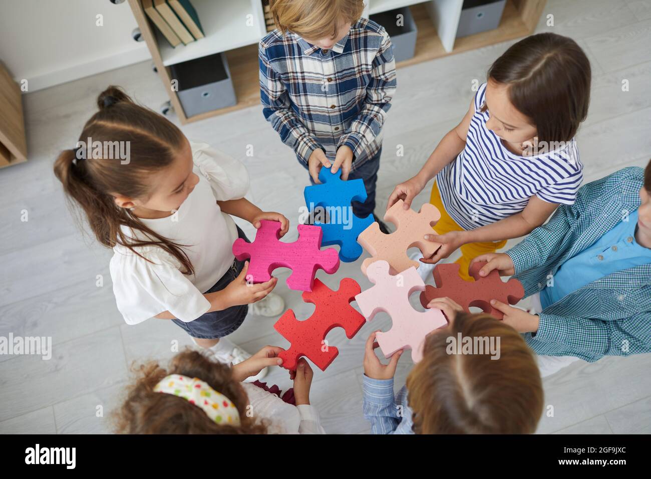 Team von kleinen Kindern stehen im Kreis und versuchen, Teile des Puzzles zu verbinden Stockfoto