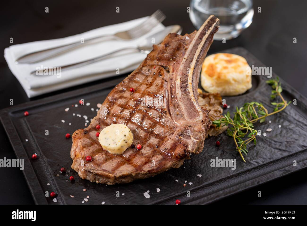 Gegrilltes Kalbsschnitzel auf schwarzem Steinteller mit Sauce und Garnitur. Stockfoto