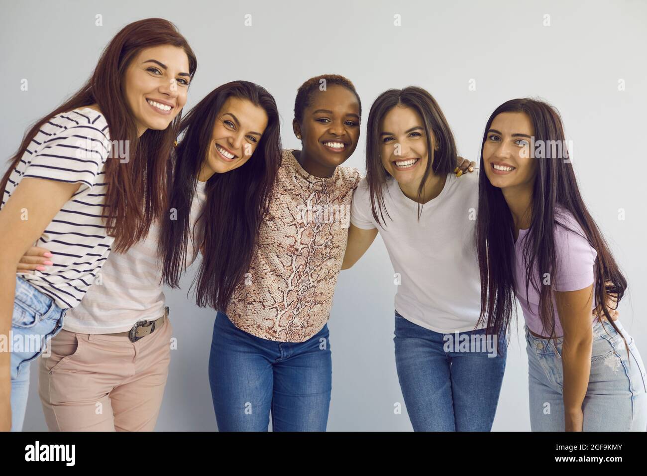 Porträt von fünf jungen, multirassischen Frauen, die zusammen stehen und vor der Kamera lächeln. Stockfoto
