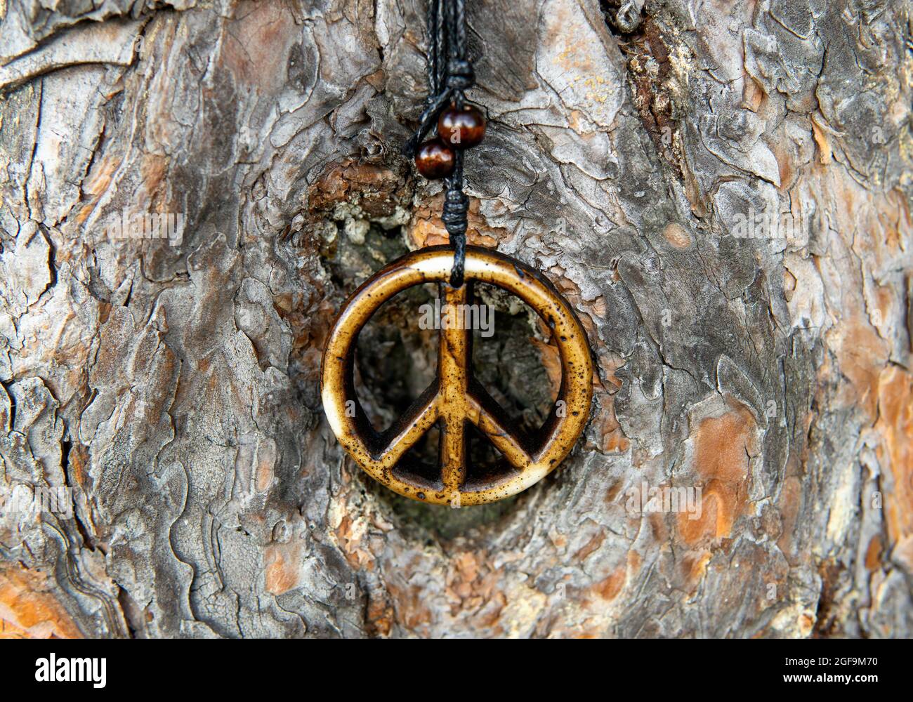Nahaufnahme einer Friedensszeichenkette vor einem strukturierten Baumrindenhintergrund, selektiver Fokus Stockfoto