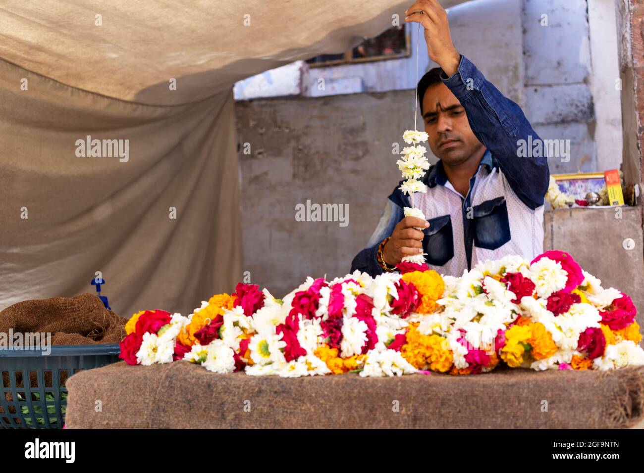 Jodhpur, Indien - 28. Februar 2018: Indiens Mann macht eine bunte Blumengirlande. Stockfoto