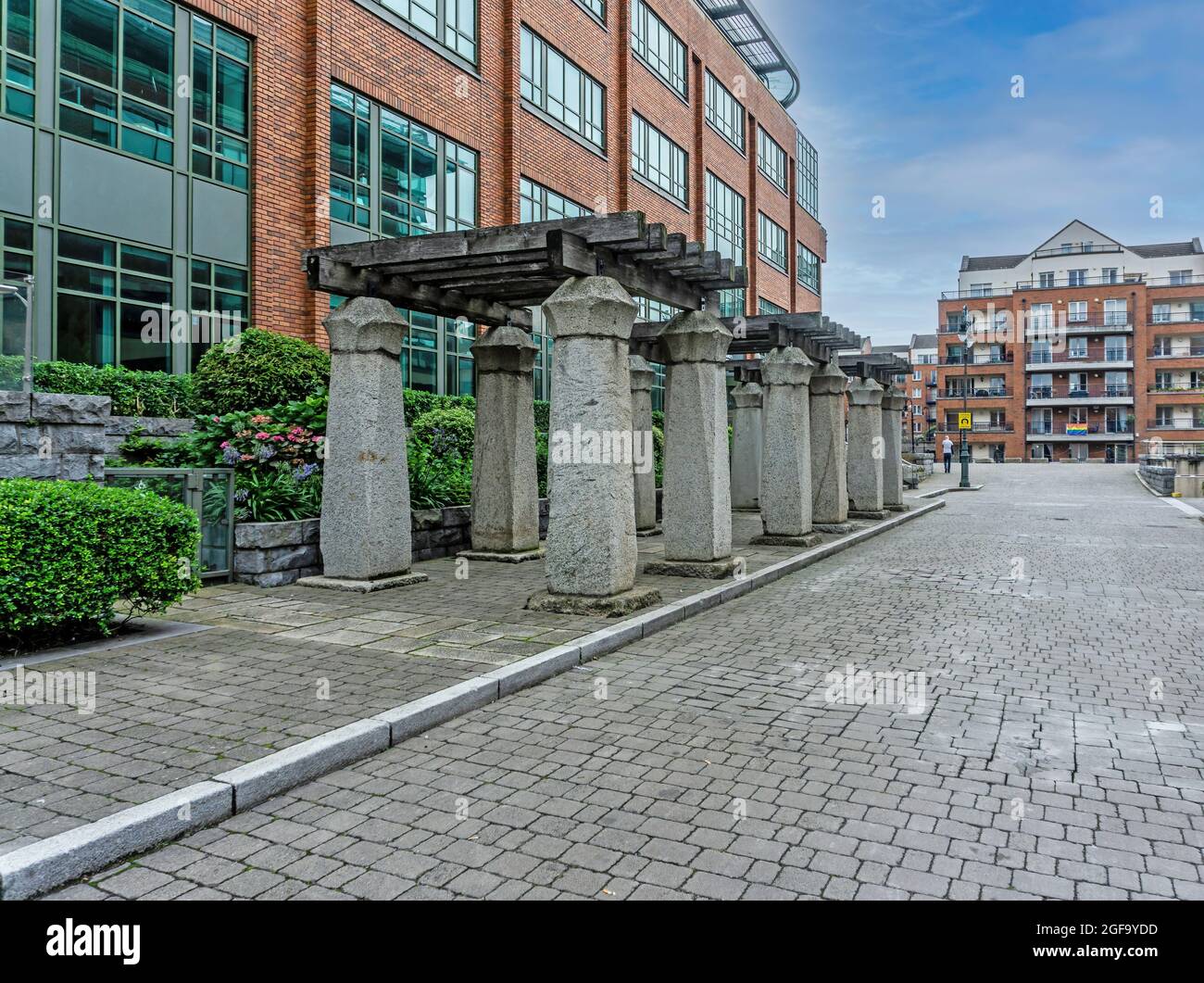 12 Steinsäulen vor 3 Georges Dock, einem Bürogebäude, in den Docklands von Dublin, Irland. Stockfoto