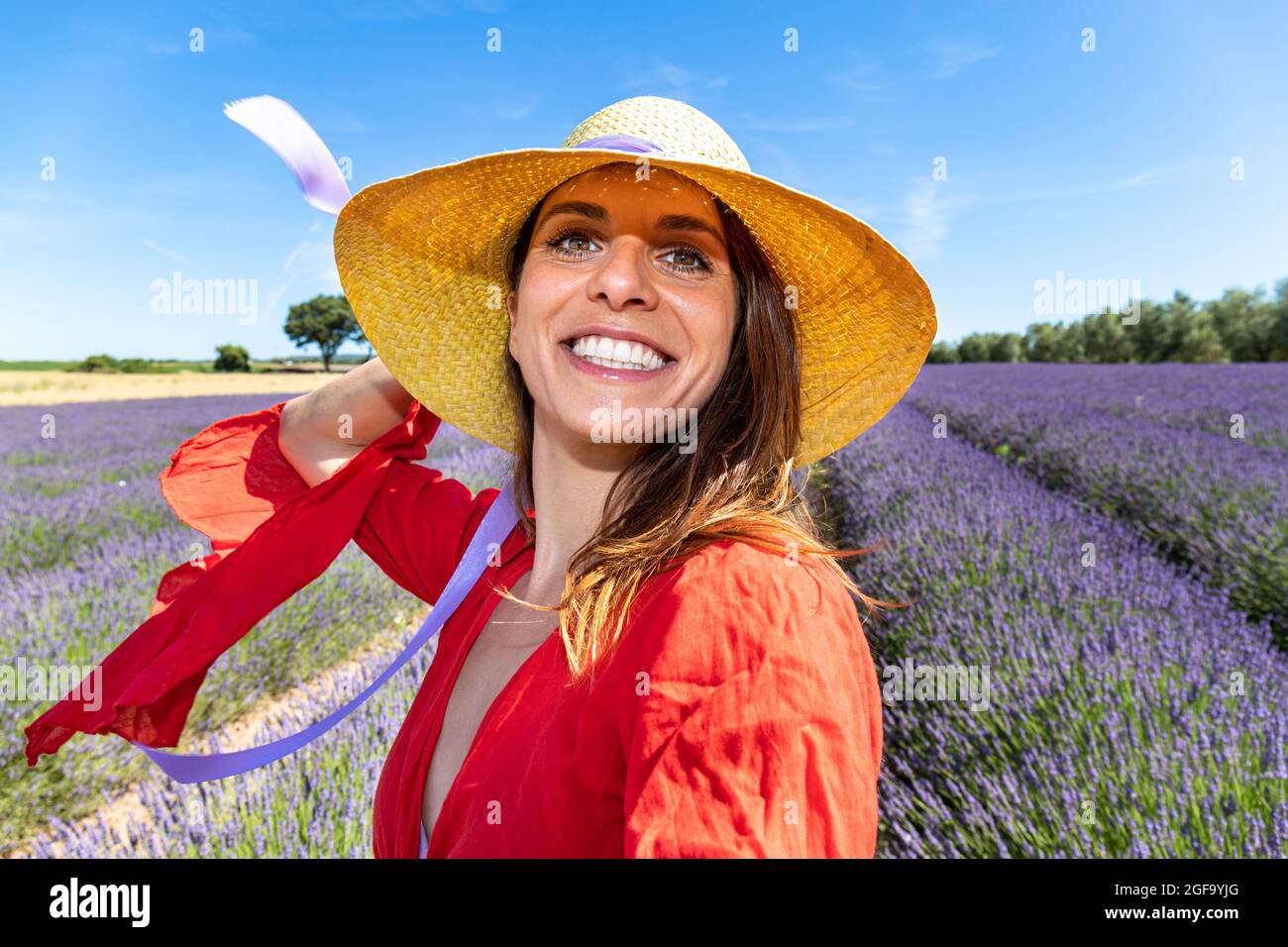 Junge lächelnde Frau mit einem Strohhut, die ein Selfie in einem blühenden Lavendelfeld nimmt. Konzept von Glück und Wohlbefinden. Stockfoto