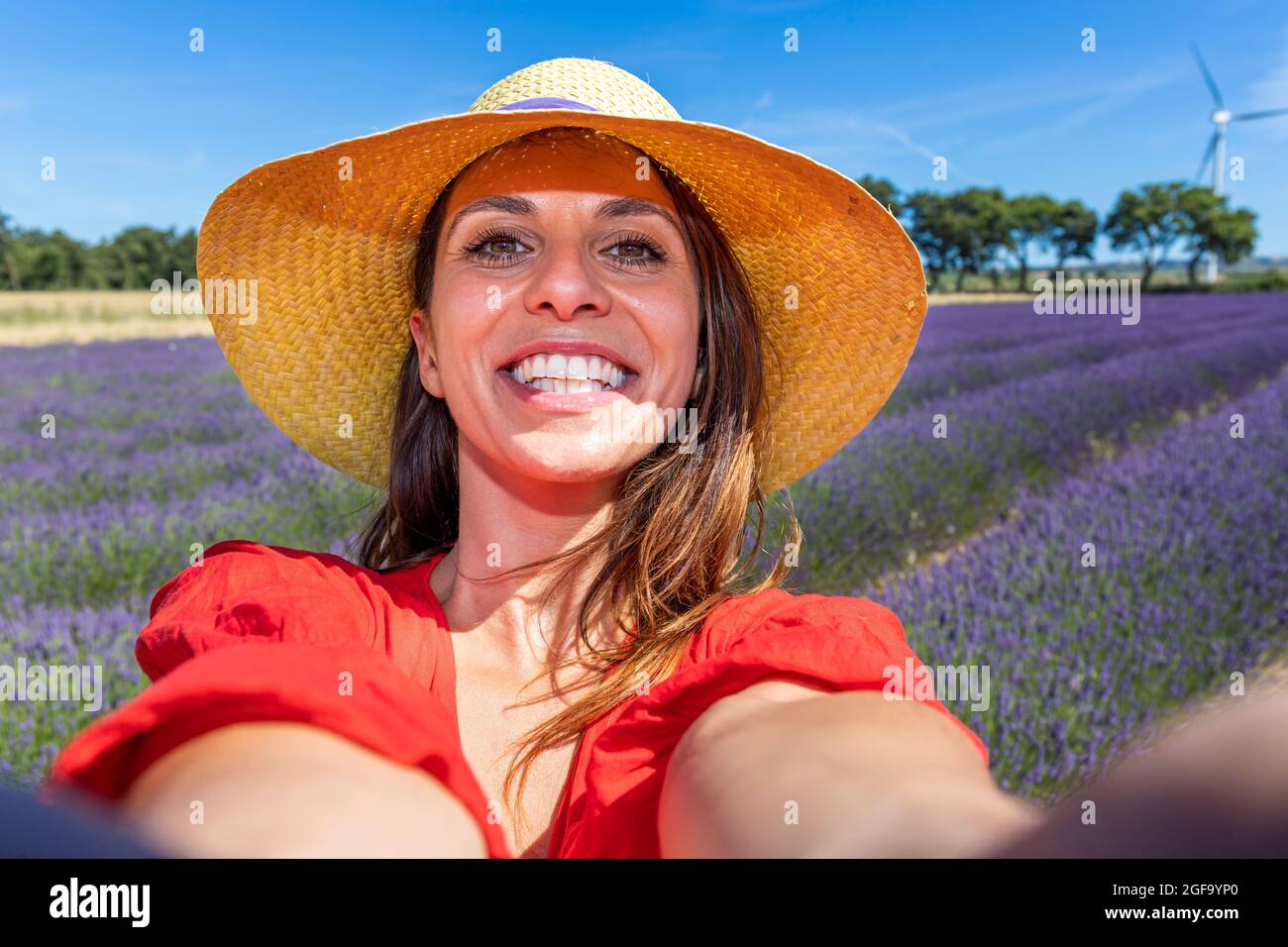 Schöne lächelnde Frau mit einem Strohhut, die ein Selfie in einem blühenden Lavendelfeld nimmt. Konzept von Glück, Wohlbefinden und Freiheit. Stockfoto