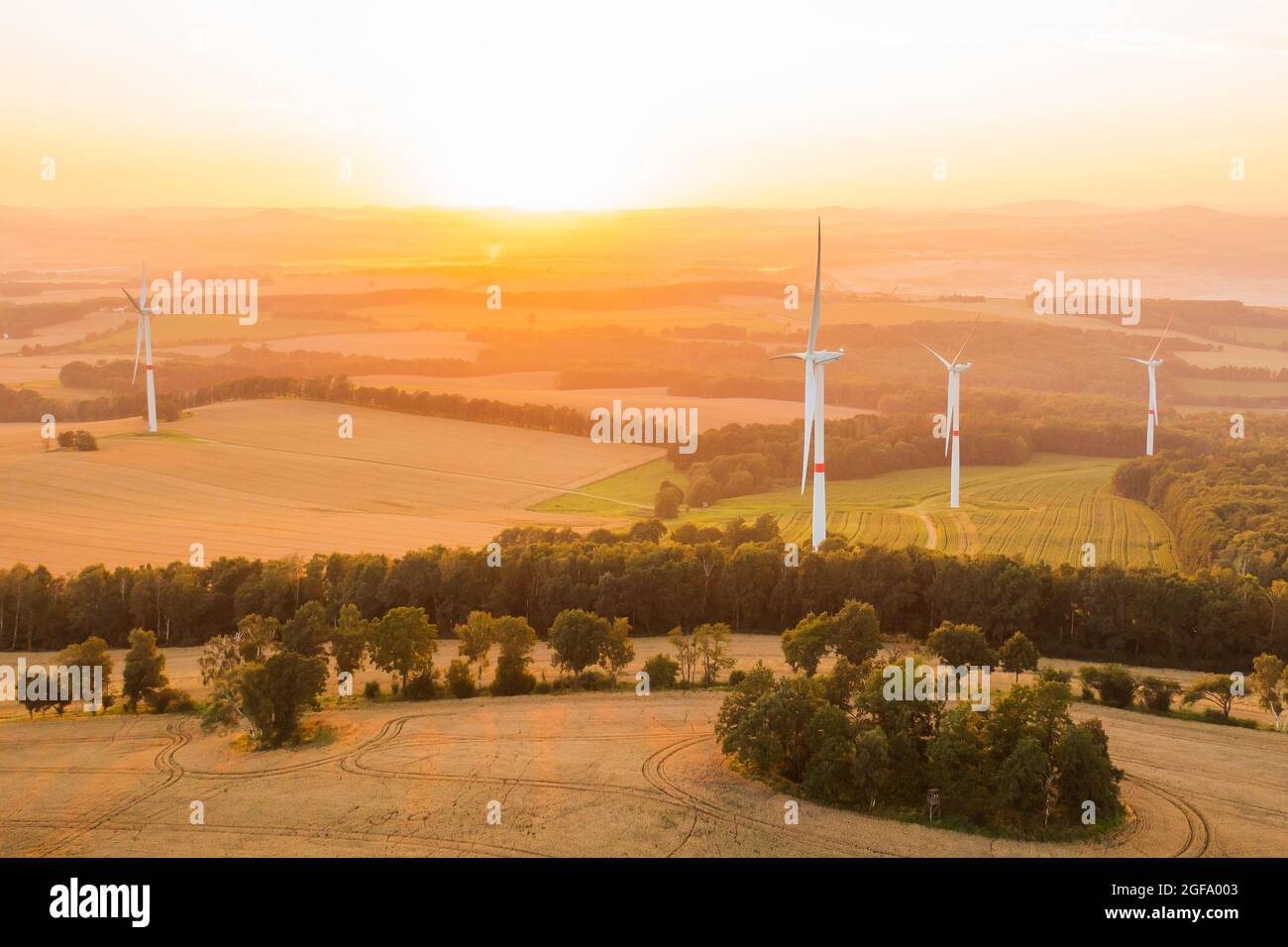 Panoramablick auf Windmühlen oder Windkraftanlagen für die Stromerzeugung bei herrlichem Sonnenuntergang auf dem Feld. Umweltfreundliche Erzeugung erneuerbarer Energien. Stockfoto