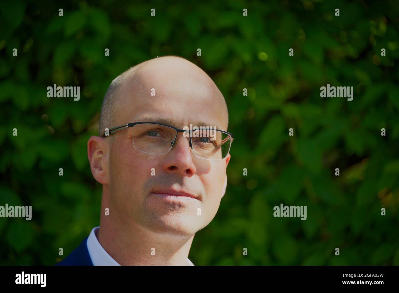 Porträt eines jungen Mannes vor dem grünen Hintergrund, der hoch aussieht Stockfoto