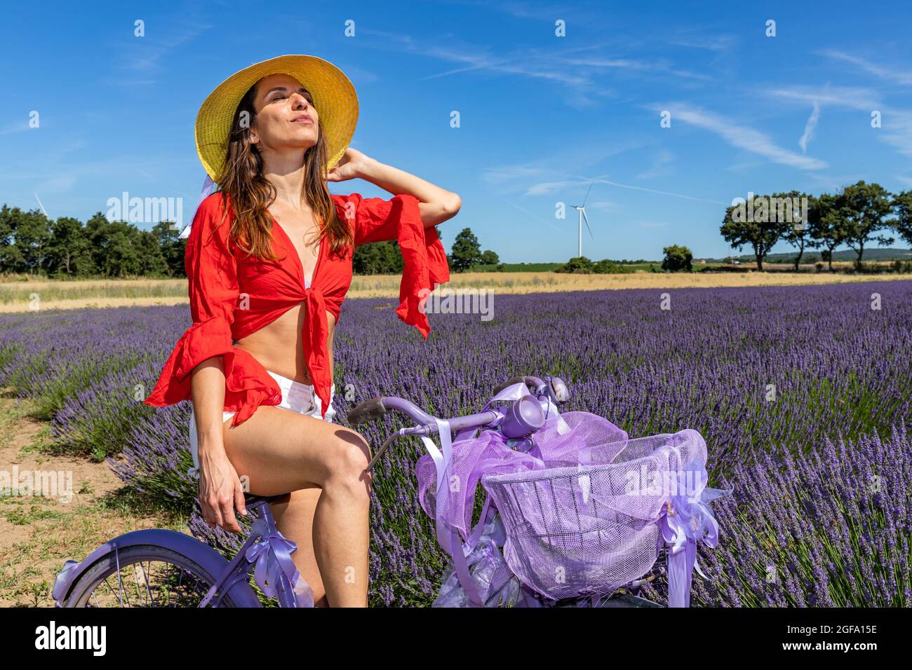 Eine junge Frau schließt die Augen und riecht den köstlichen Duft einer Lavendelblüte. Konzept von Wohlbefinden und Liebe zur Natur. Stockfoto