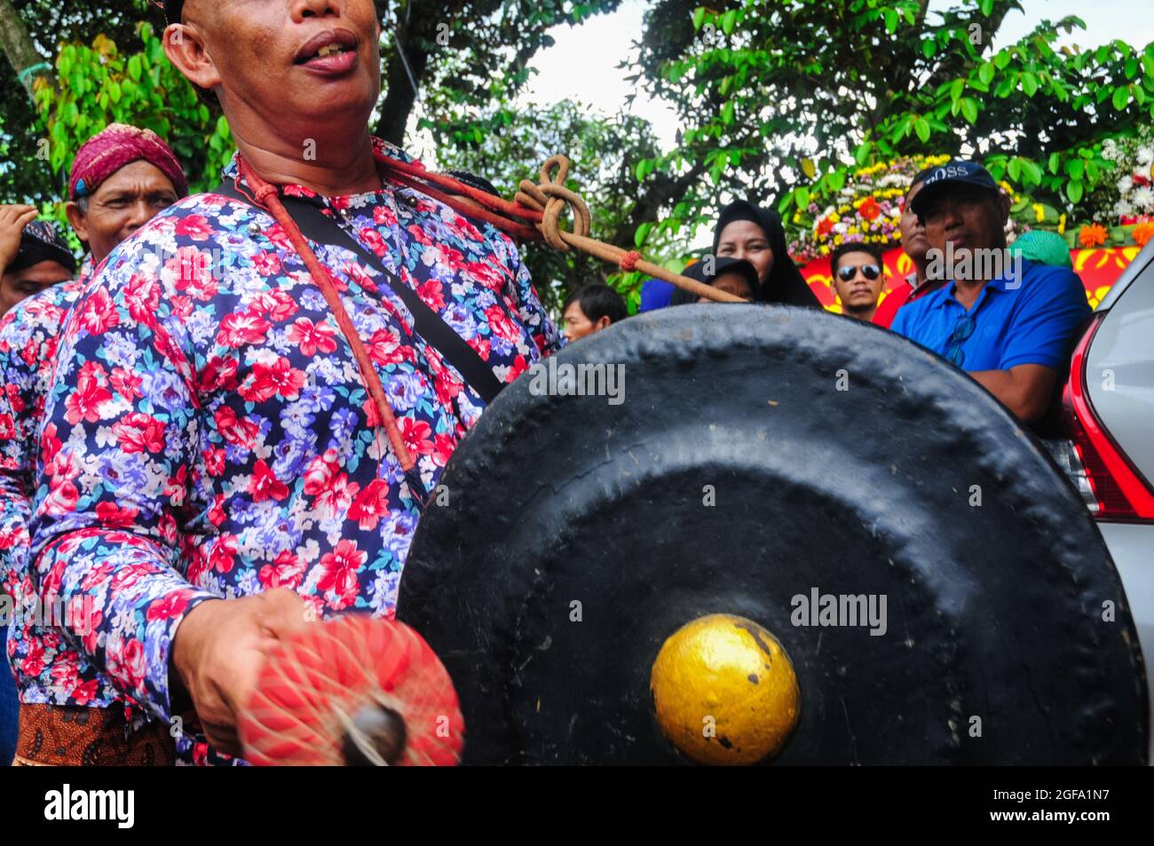 Ein gong-Spieler in einer Gruppe von Musikern, der die Kunst des Reogs begleitet, während er am Karneval teilnimmt. Stockfoto