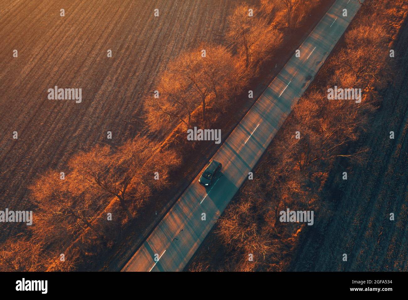 Auto, das bei Sonnenuntergang die Straße hinunter fährt, Luftaufnahme von Drohne pov, wunderschöne Landschaft Stockfoto