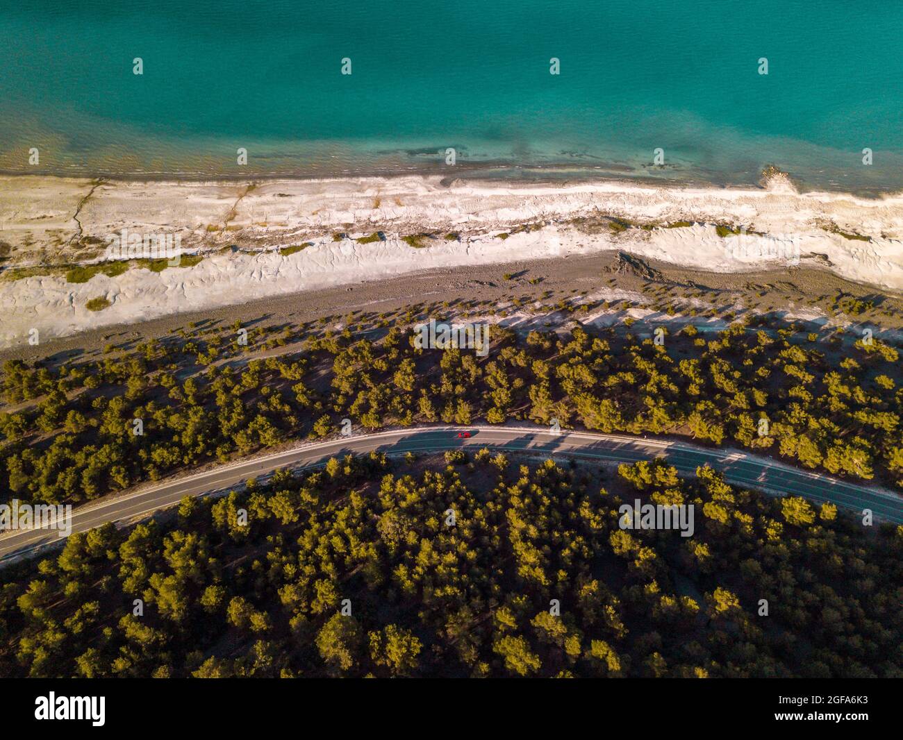 Luftaufnahme eines Strandes, umgeben von Grün und Meer unter dem Sonnenlicht Stockfoto