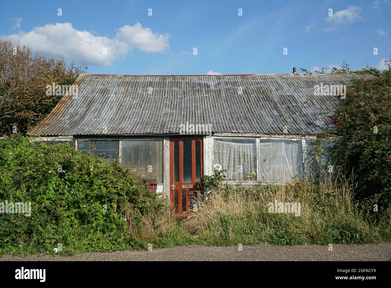 East Wittering, Großbritannien, 24. August 2021: Ein winziger Bungalow mit einem Wellblechdach sitzt zwischen Brambles und Unkraut, ist aber immer noch bewohnt. Mehrere Bungalows in der Gegend sind um gebrauchte Eisenbahnwaggons gebaut und dieser ist es möglicherweise auch. Anna Watson/Alamy Stockfoto