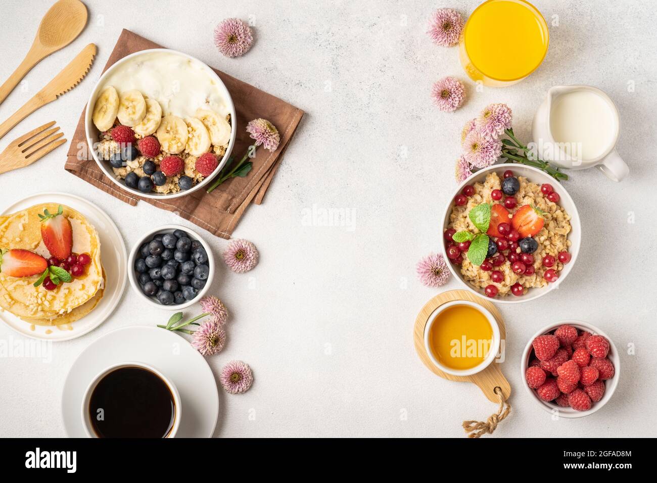 Ein Tisch für ein gesundes Frühstück mit Pfannkuchen, Müsli, frischen Beeren, Kaffee mit Milch und Orangensaft. Draufsicht. Stockfoto