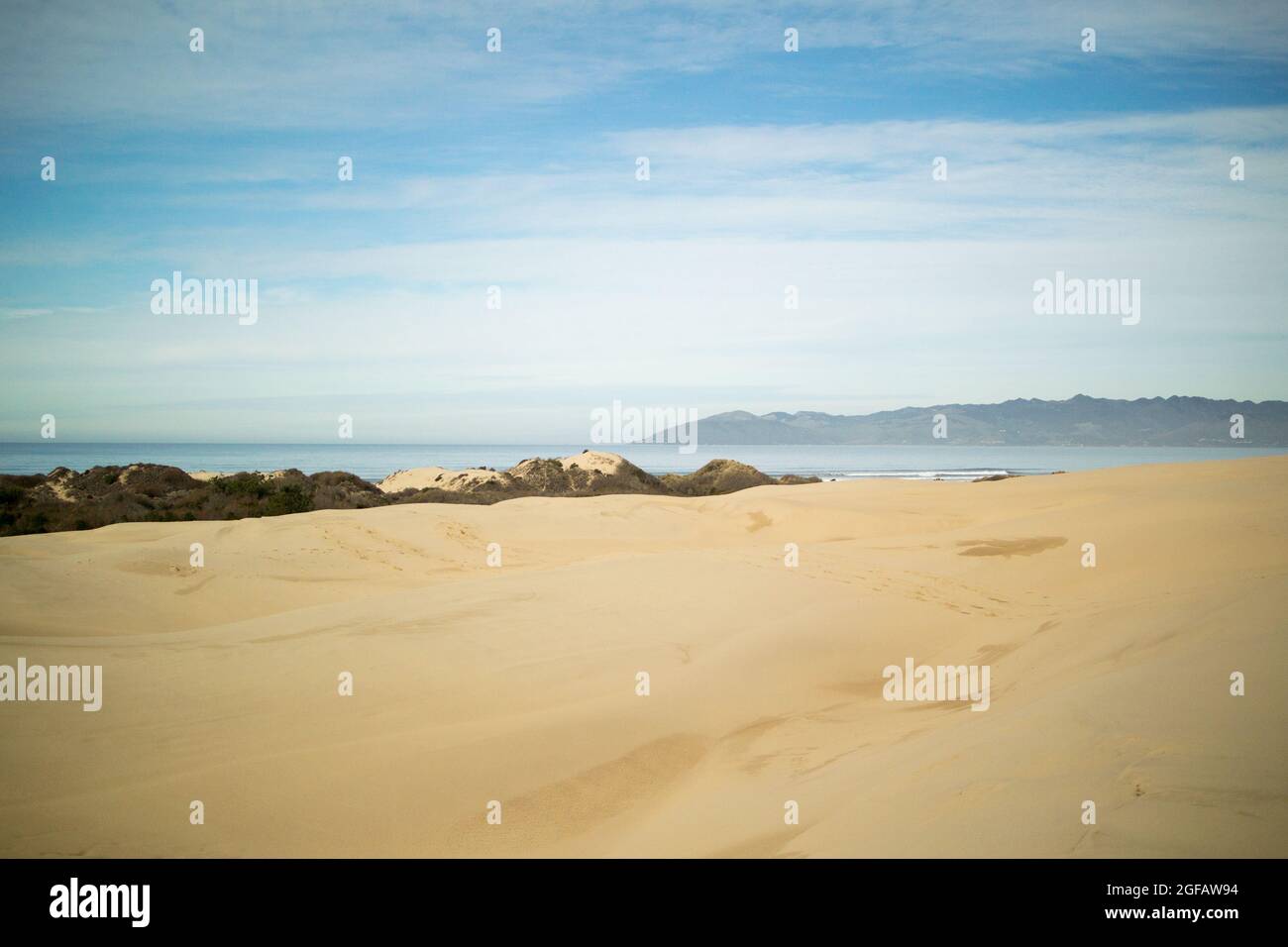 Sanddünen, die am bewölkten Wintertag zum Pazifischen Ozean führen, mit trüben grauen Bergen am Horizont Stockfoto