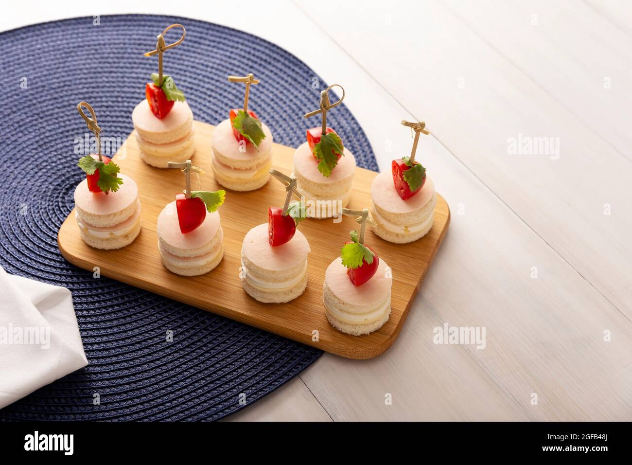 Leckere Party-Snacks. Runde Mini-Sandwiches mit Schinken und Käse, verziert mit Kirschtomaten auf einem Bambusstock Stockfoto