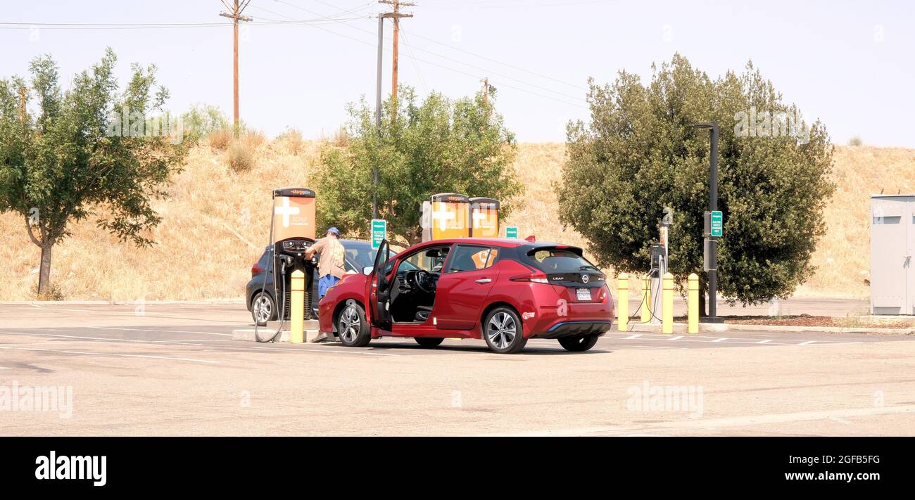 Mann lädt ein Nissan Leaf Elektrofahrzeug an einer ChargePoint Express DC Schnellladestation auf einem Parkplatz an einer Autobahn in der Nähe von Gilroy, Kalifornien. Stockfoto