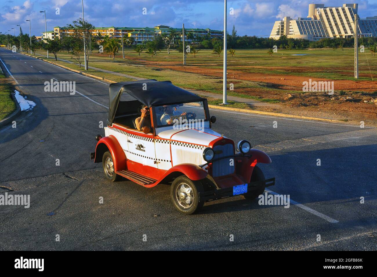Varadero, Kuba - 3. Februar 2010: Vintage-Taxi fährt aus Melia Las Antillas Resort. Das Blau Varadero Resort befindet sich auf der rechten Seite. Stockfoto