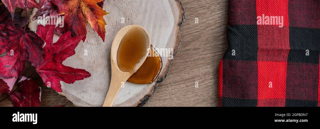 Ahornsirup süße Zutat für Dessert Rezepte, Flüssigkeit tropft aus Holzlöffel auf Holz log rustikalen Zucker Shack Banner Panorama mit Büffel Stockfoto