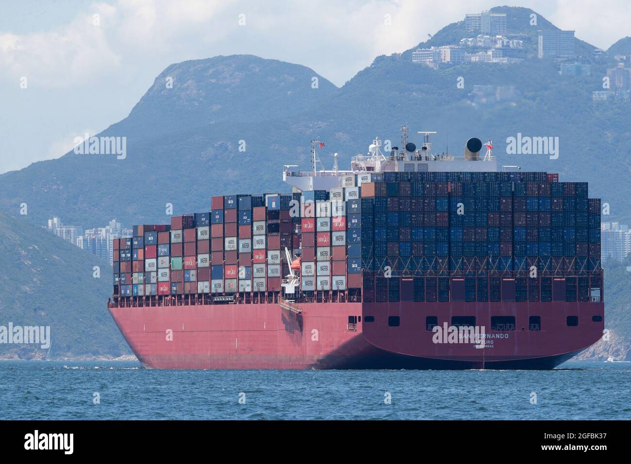 Containerschiff „San Fernando“, (Reg. Marshallinseln), im East Lamma Channel, Mt Kellett, Hong Kong im Hintergrund, Hong Kong China 22. August 2021 Stockfoto