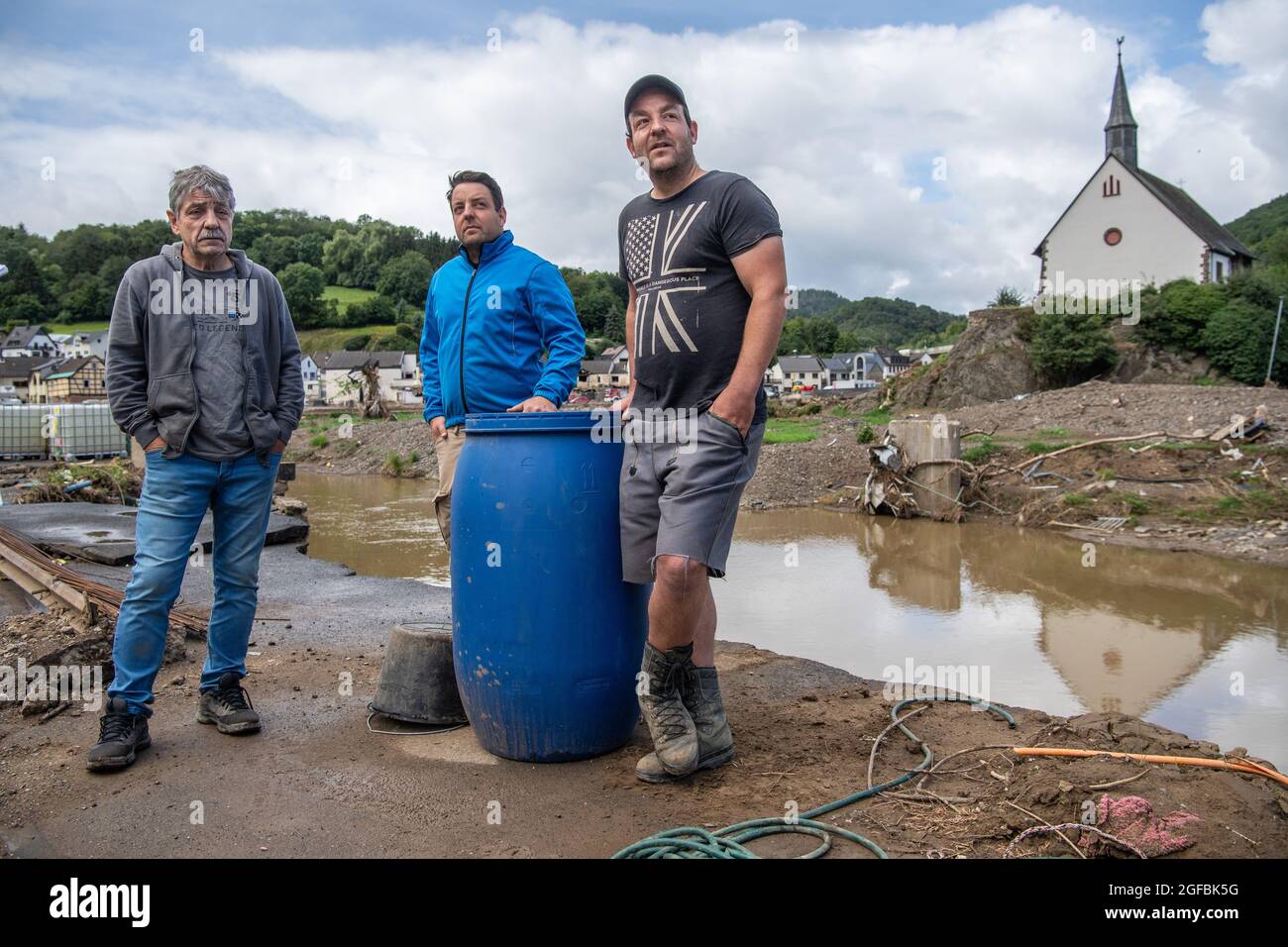 Altenahr, Deutschland. August 2021. Der 69-jährige Bernd Gasper steht mit seinen Söhnen Achim (m) und Oliver am Ufer der Ahr. Die Familie verlor ihr Elternhaus in der Flut. In der Zwischenzeit hat ein Experte den Abriss des Gebäudes empfohlen. (To dpa 'sechs Wochen nach der Flut: 'Die Region braucht eine Perspektive' aus dem Jahr 25.08.2021) Quelle: Boris Roessler/dpa/Alamy Live News Stockfoto