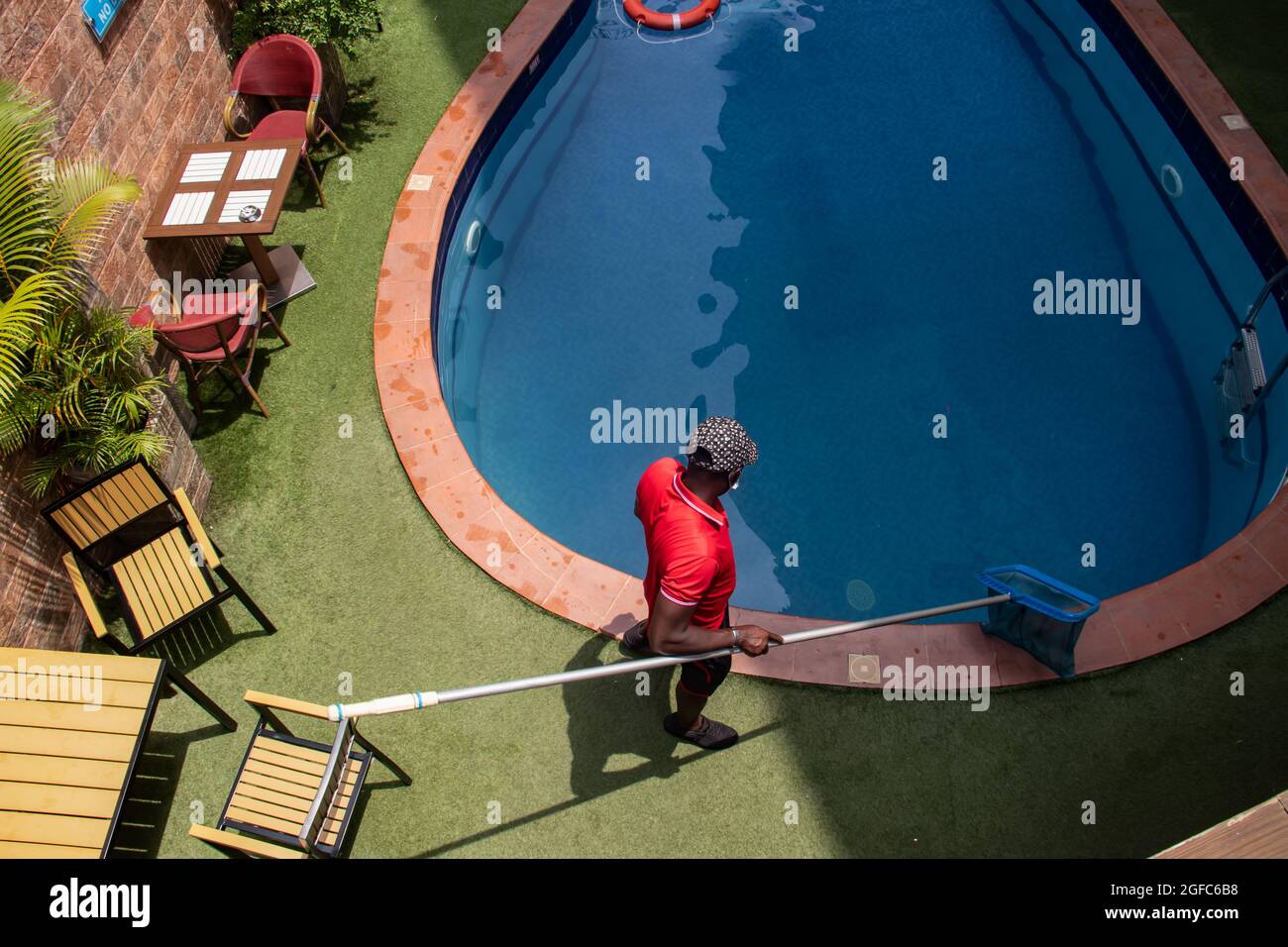 Reinigung des Schwimmbads durch den Pool-Typen, mit Netz. Dekorative Pflanzen neben dem Swimmingpool Stockfoto